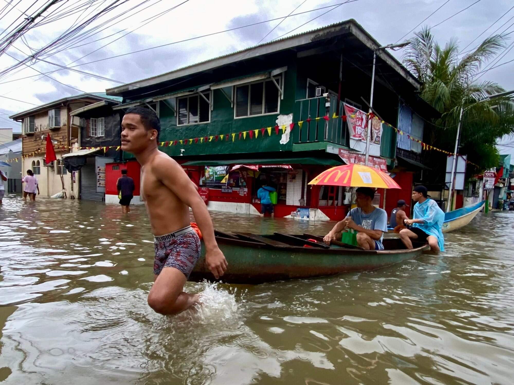 People make their way through floodwater in Kawit, Cavite province, south of Manila, Philippines. Photo: EPA