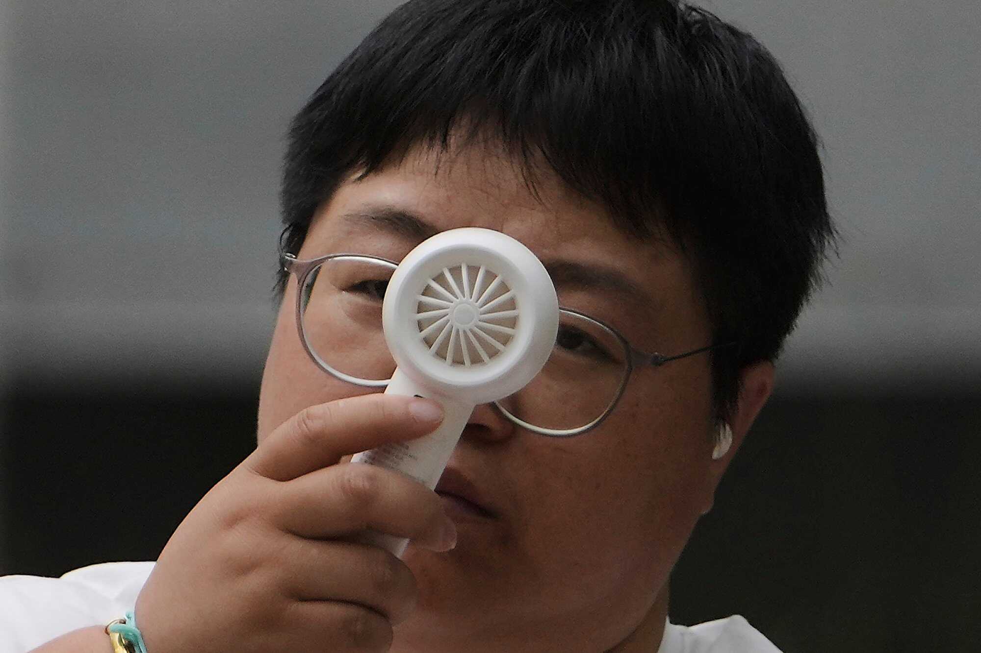 A woman cools herself with a portable electric fan on a sweltering day in Beijing, China. Photo: AP
