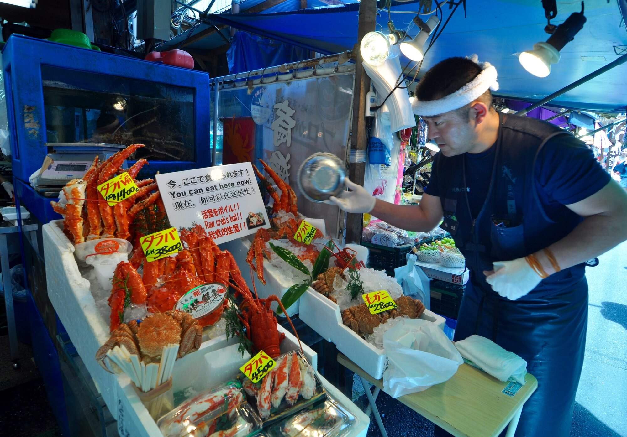 A shopkeeper pours ice onto red king crabs to keep them fresh at a market in Tokyo, Japan. Photo: Daniel Hurst