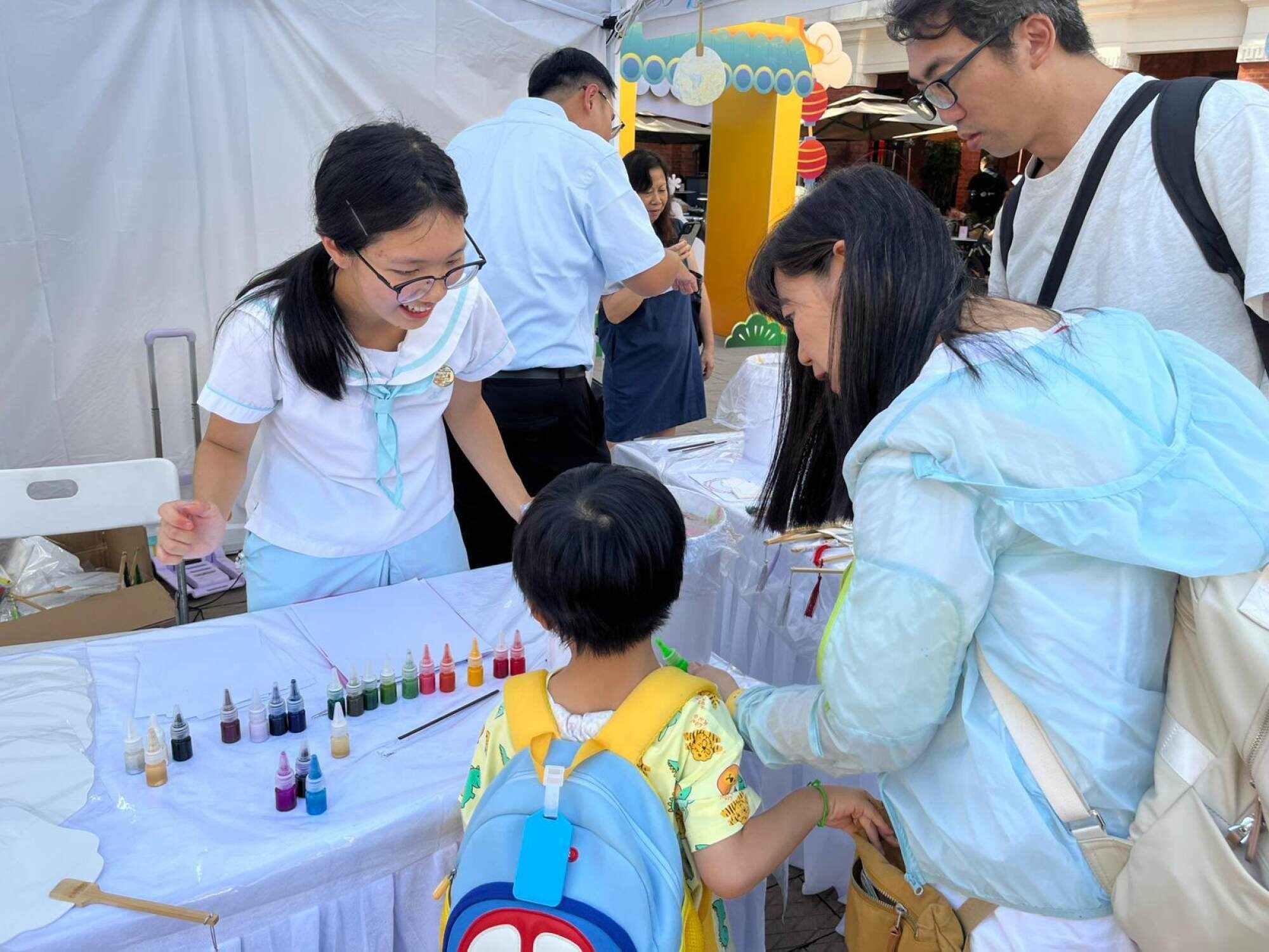 Celine Li (left) guides visitors in creating their own lacquered fans. Photo: Leah Lei