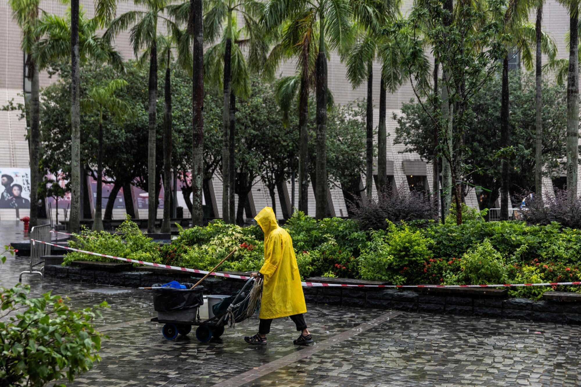 A worker pushes a trolley near the waterfront in Tsim Sha Tsui during Typhoon Podul. Photo: AFP