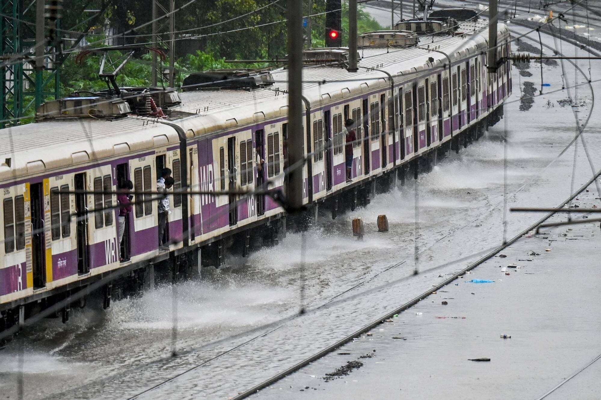 A local train rides through flooded railway tracks during heavy rain showers in Mumbai on August 18. Photo: AFP