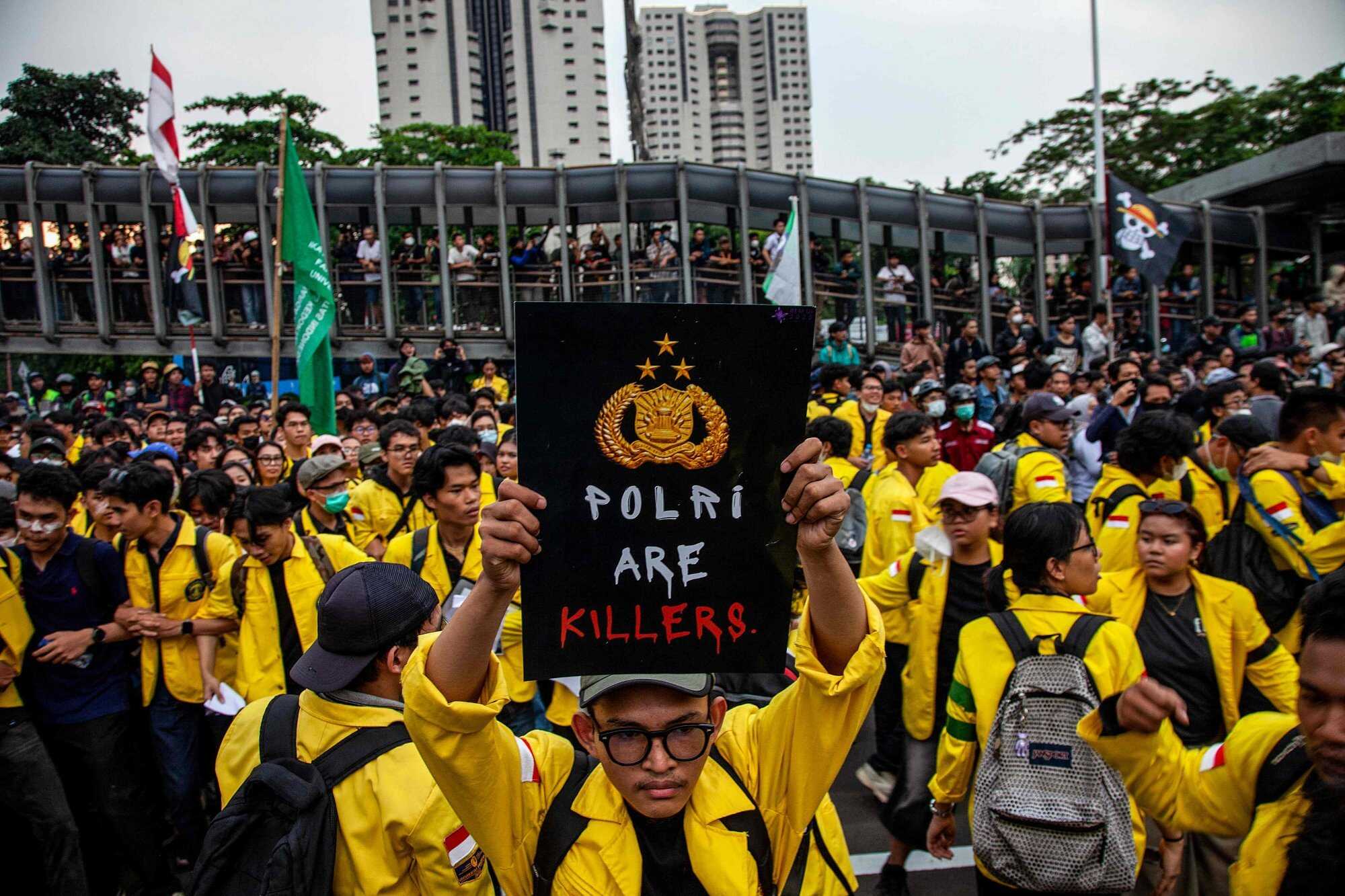 A university student holds a poster reading ‘Police are killers’ during a protest against police. Photo: AFP