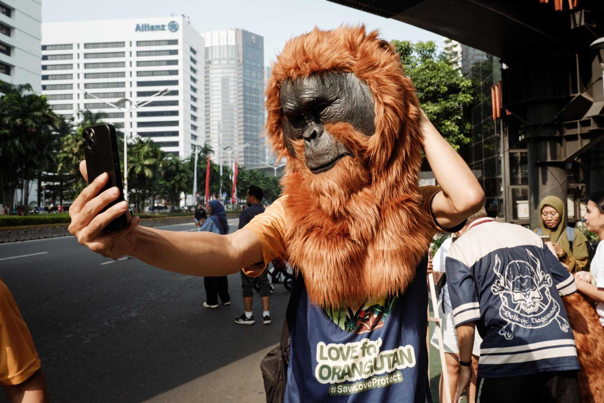 A participant takes selfies with an orangutan mascot head as he attends an awareness action calling for the protection of orangutans to mark World Orangutan Day. Photo: AFP