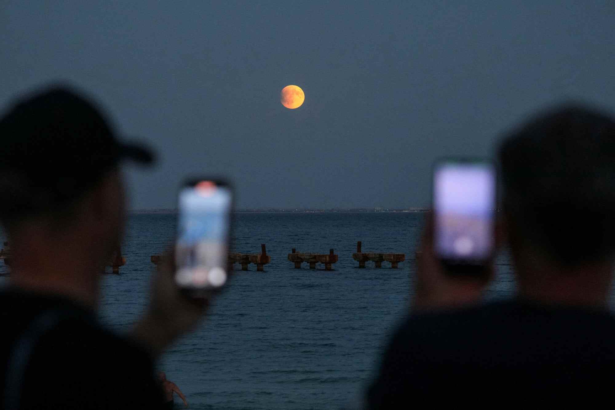 People take pictures as the “blood moon” rises over the Black Sea during a total lunar eclipse in Crimea. Photo: Reuters