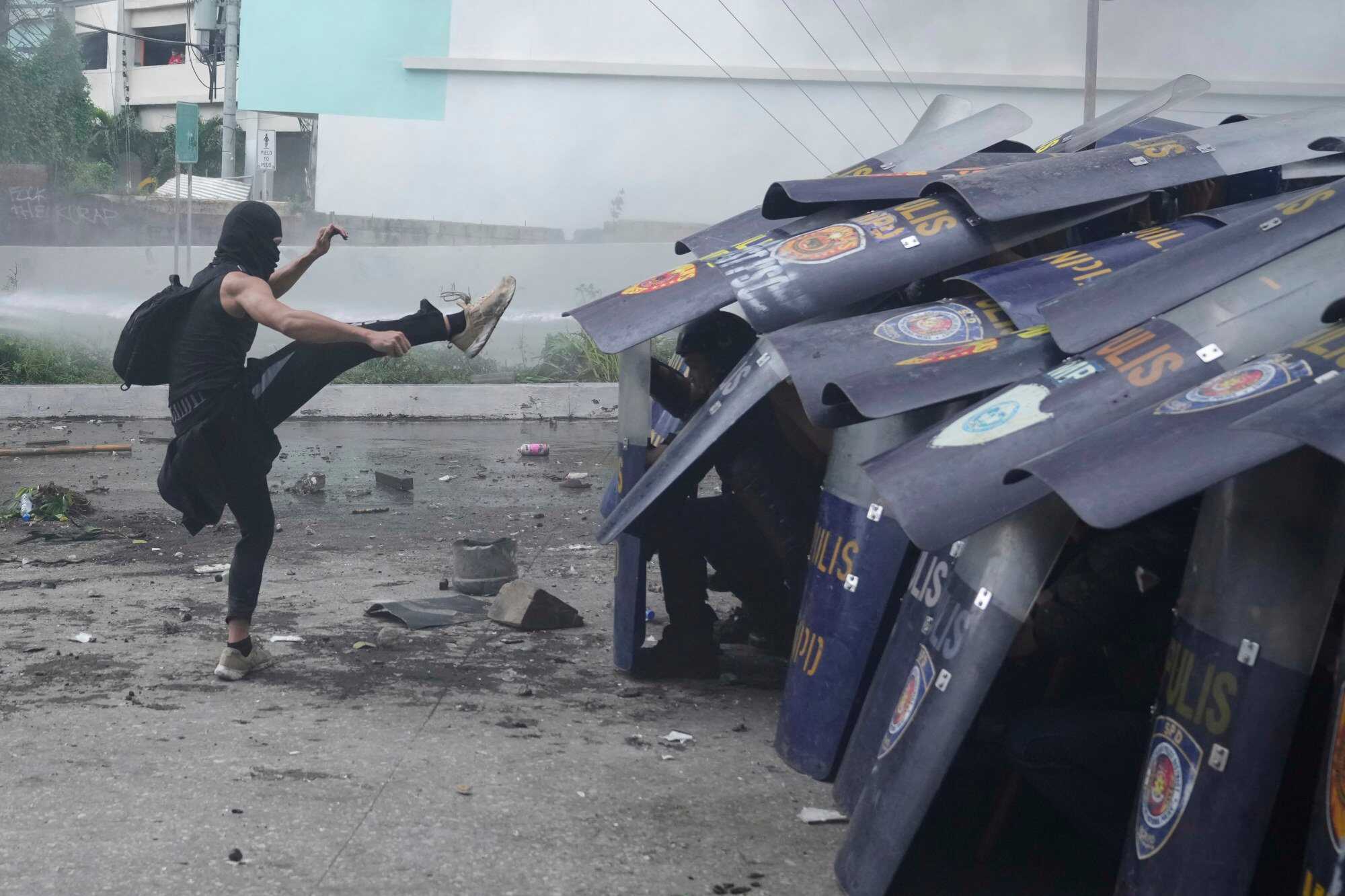 An anti-corruption protester kicks the shield of a policeman during clashes in Manila, Philippines. Photo: AP
