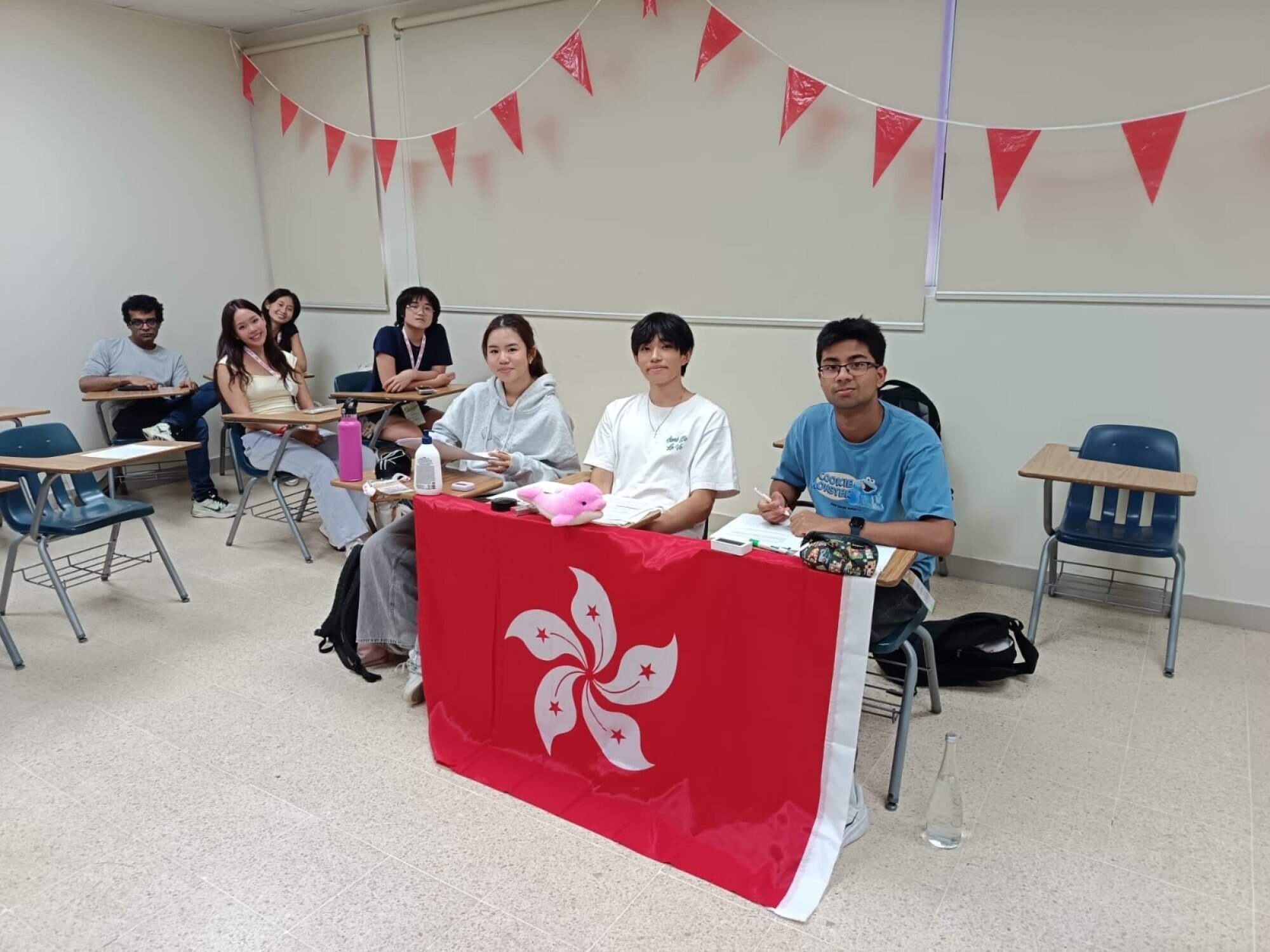 Mollie Mei (from left), Junhyun Nam and Advik Sharma sit together at a desk and prepare to debate. Photo: Handout