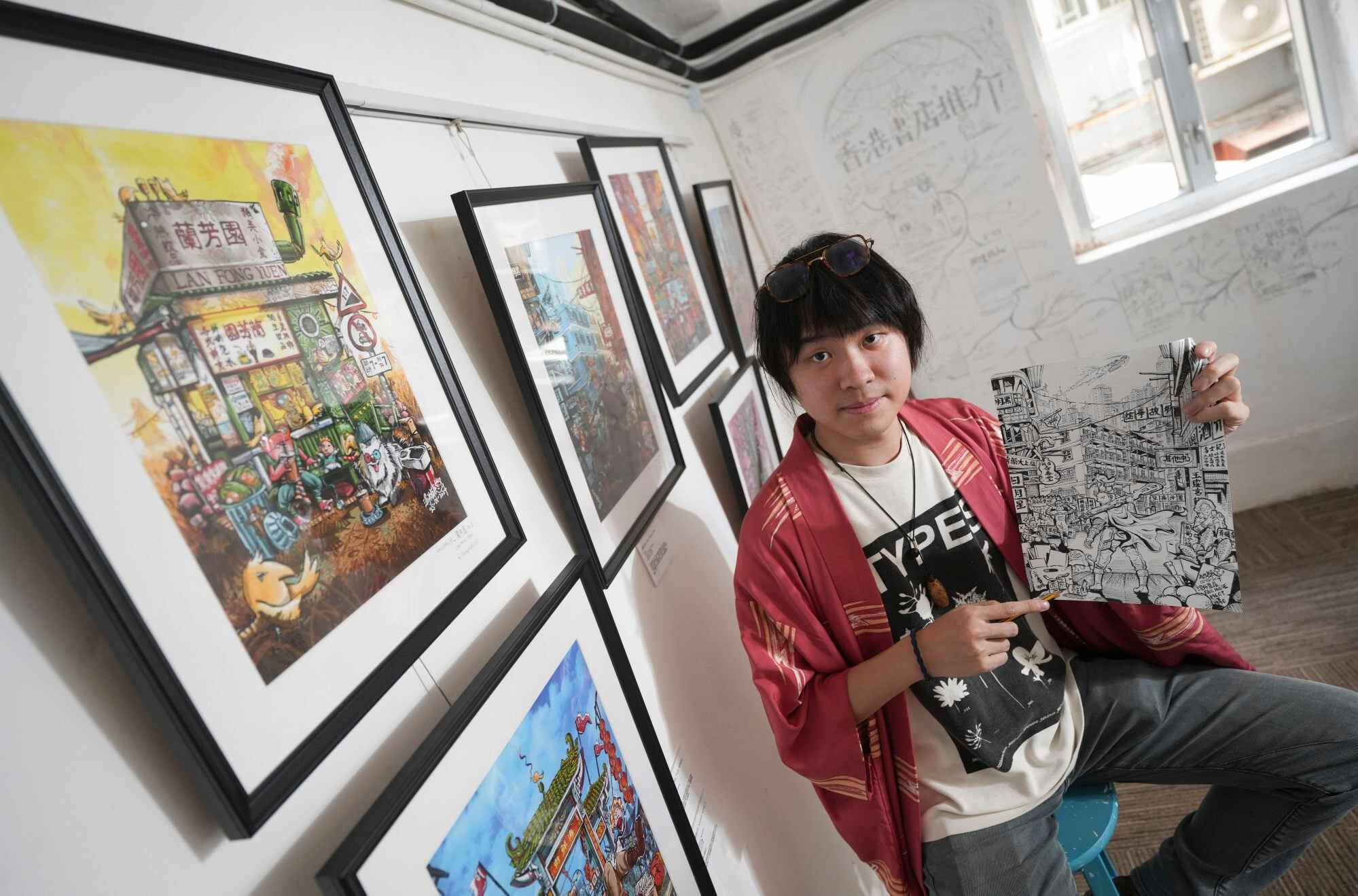 Illustrator Tommychief Oil poses with some of his work. Photo: Sun Yeung