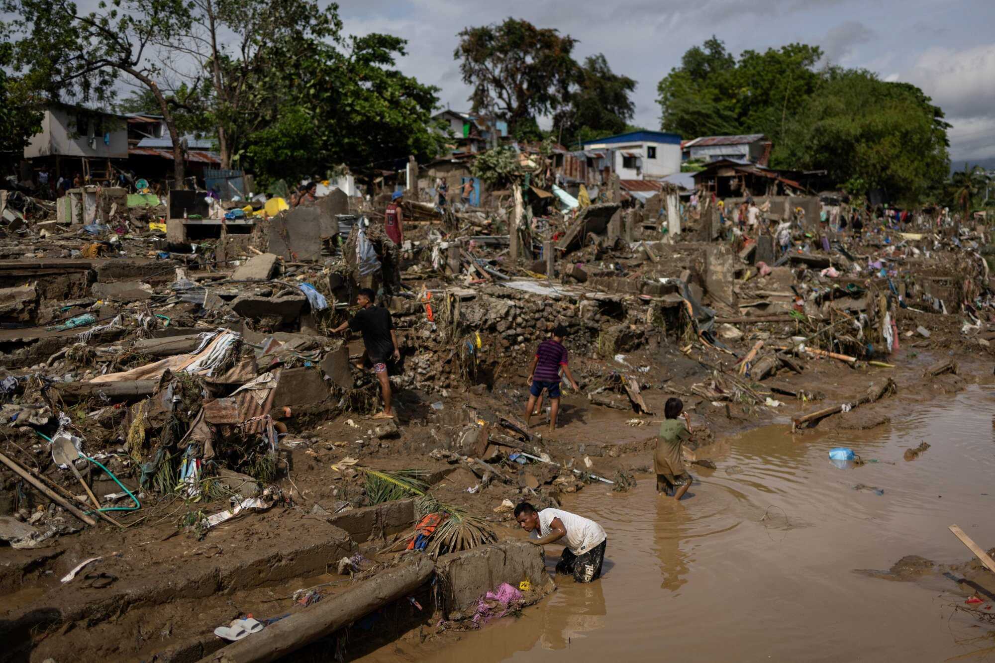 A man fishes in water swept in by the floods, while residents return to the remains of their homes in the aftermath of Typhoon Kalmaegi in Talisay, Cebu province. Photo: Reuters
