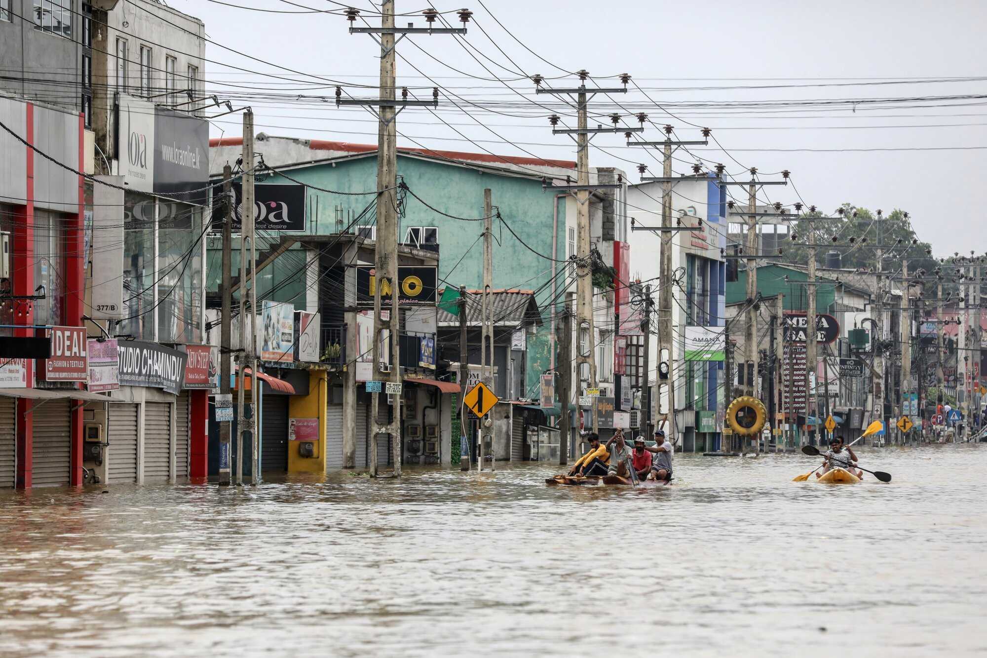 People wade through a flooded road after heavy rainfall in a suburb of Colombo. Photo: EPA