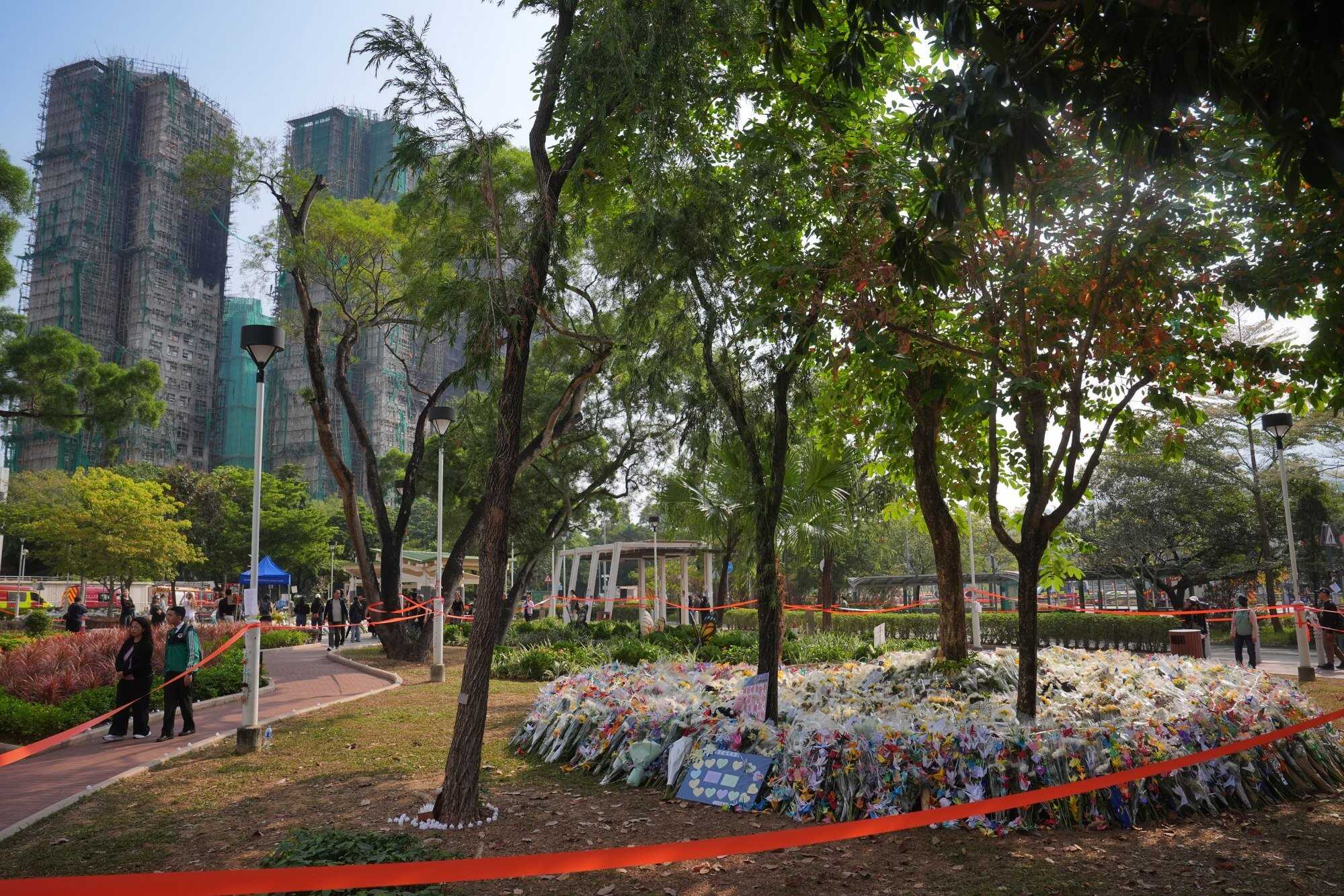 People lay flowers and paper cranes at Kwong Fuk Sitting Out Area to pay tribute to the victims of the major fire of Wang Fuk Court (in the background) in Tai Po. Photo: Elson Li