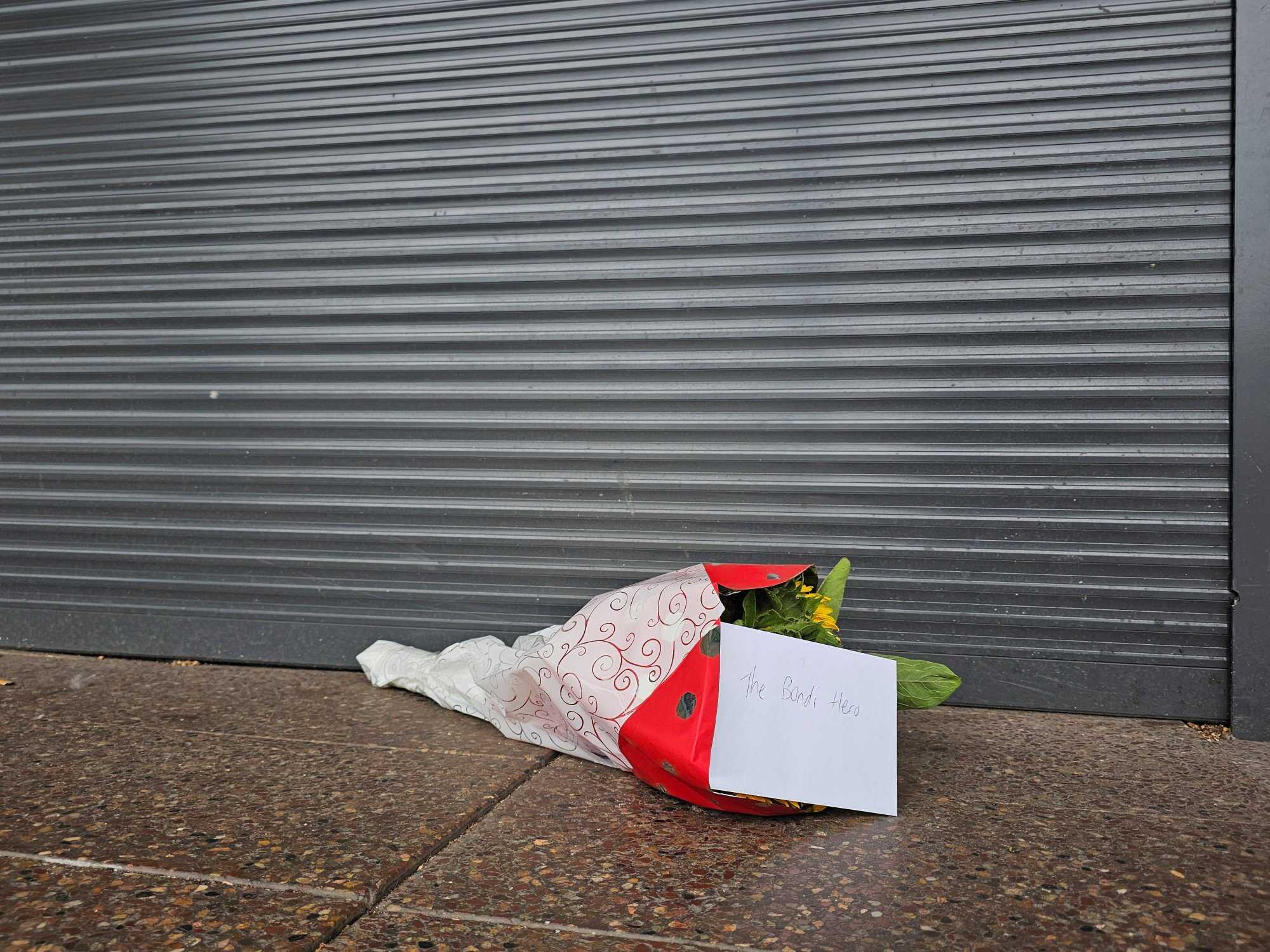 Flowers with a note that read “The Bondi Hero” are left outside a tobacco shop owned by Ahmed al Ahmed, the bystander who charged at one of the gunmen and seized his rifle during the deadly shooting at Bondi Beach in Sydney, Australia. Photo: Reuters