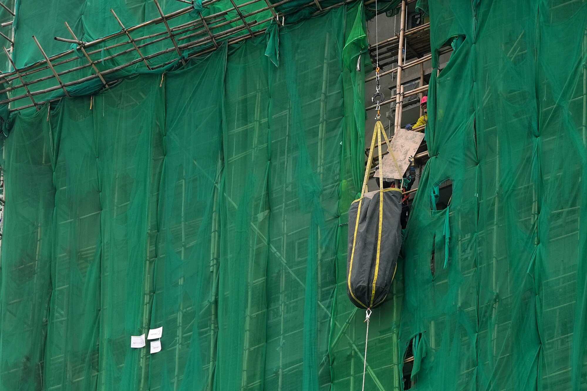 Workers remove wooden plates from the top floors of a burnt building in Wang Fuk Court, Tai Po. Photo: Elson Li