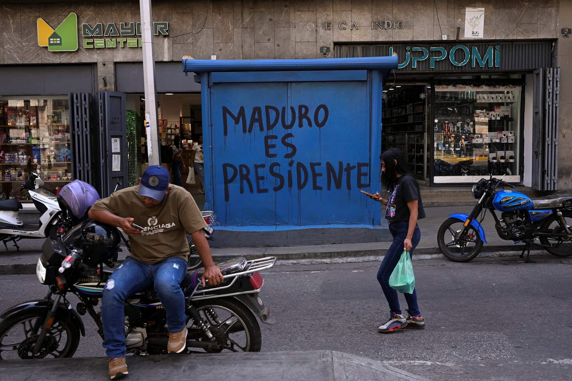 People walk in front of graffiti that reads “Maduro is president” in Caracas, Venezuela, days after the US launched a strike on Venezuela and captured President Nicolas Maduro and his wife Cilia Flores. Photo: Reuters