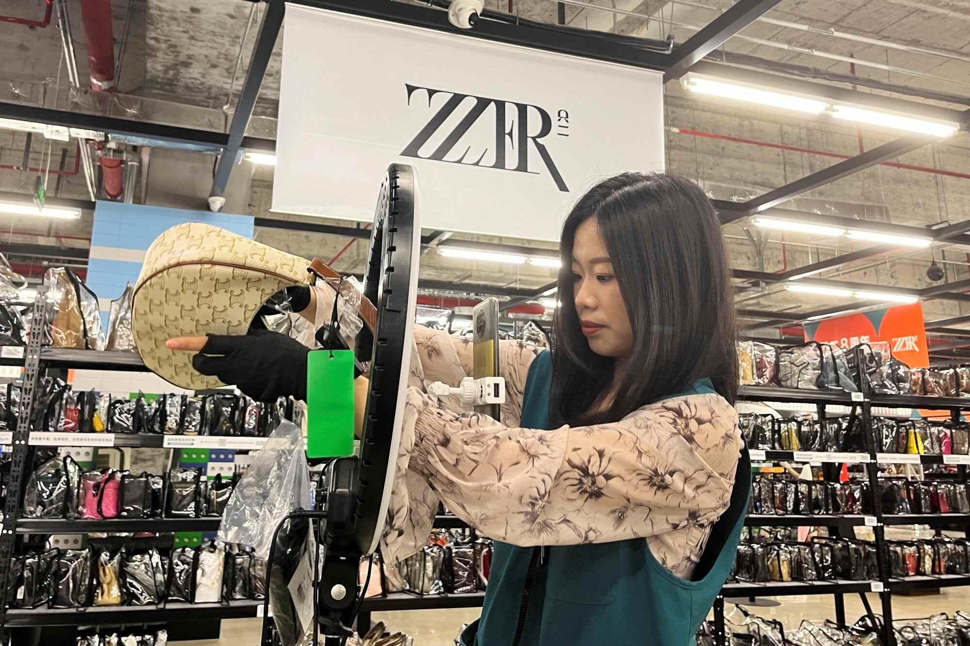 A staff member promotes a bag during a live-streaming session at a warehouse for second-hand luxury e-commerce platform ZZER in Shanghai, China. Photo: Reuters