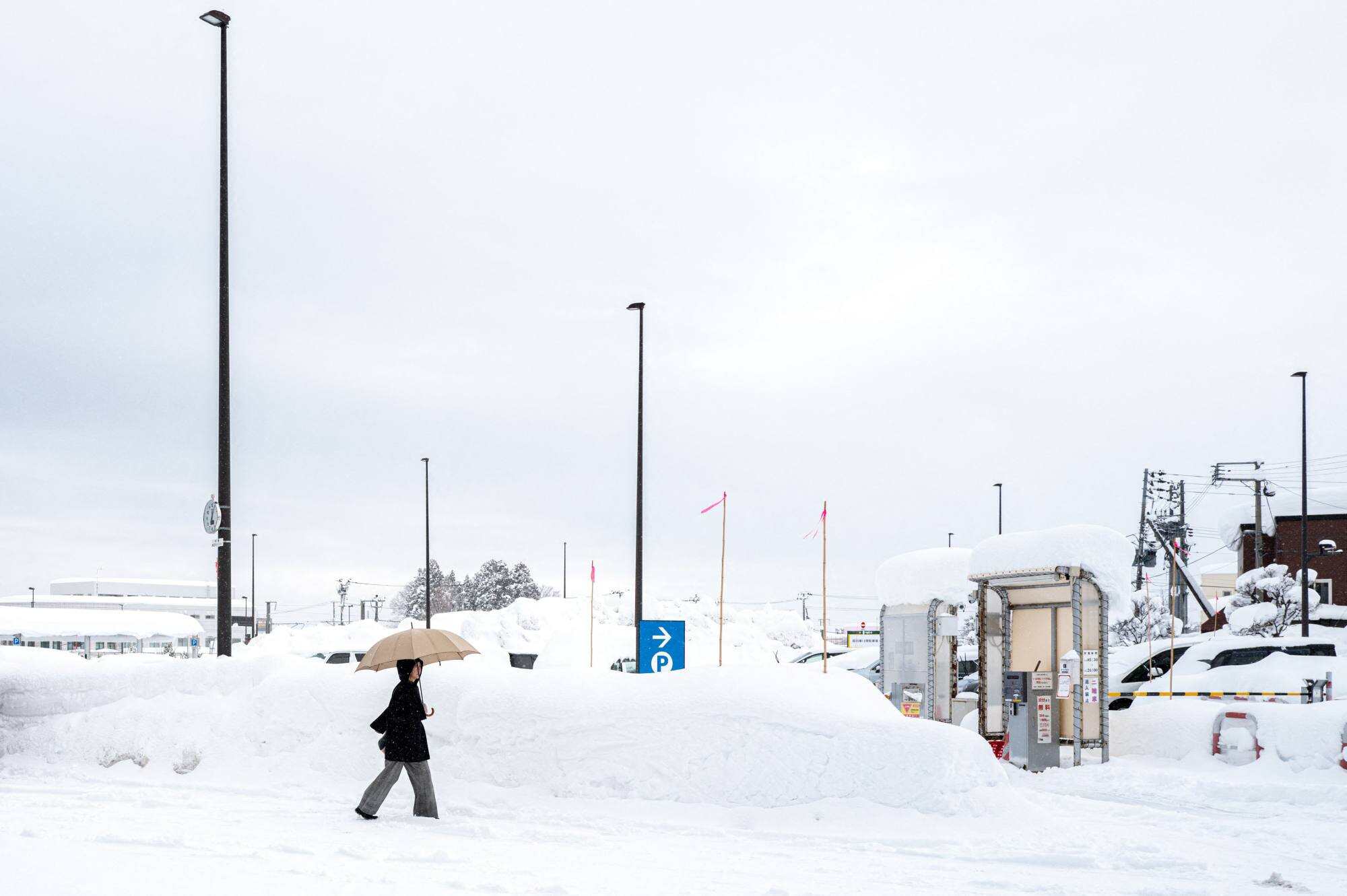 A pedestrian walks towards a snow-covered car park in Aomori City. Photo: AFP
