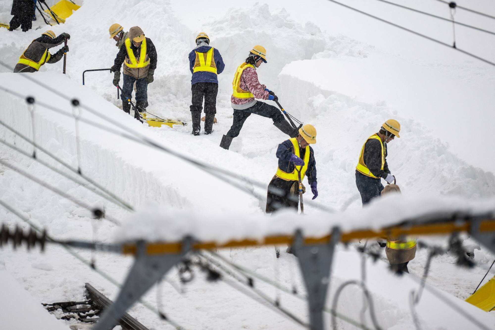 Staff members shovel snow-covered rail tracks at Shin Aomori station in Aomori City. Photo: AFP