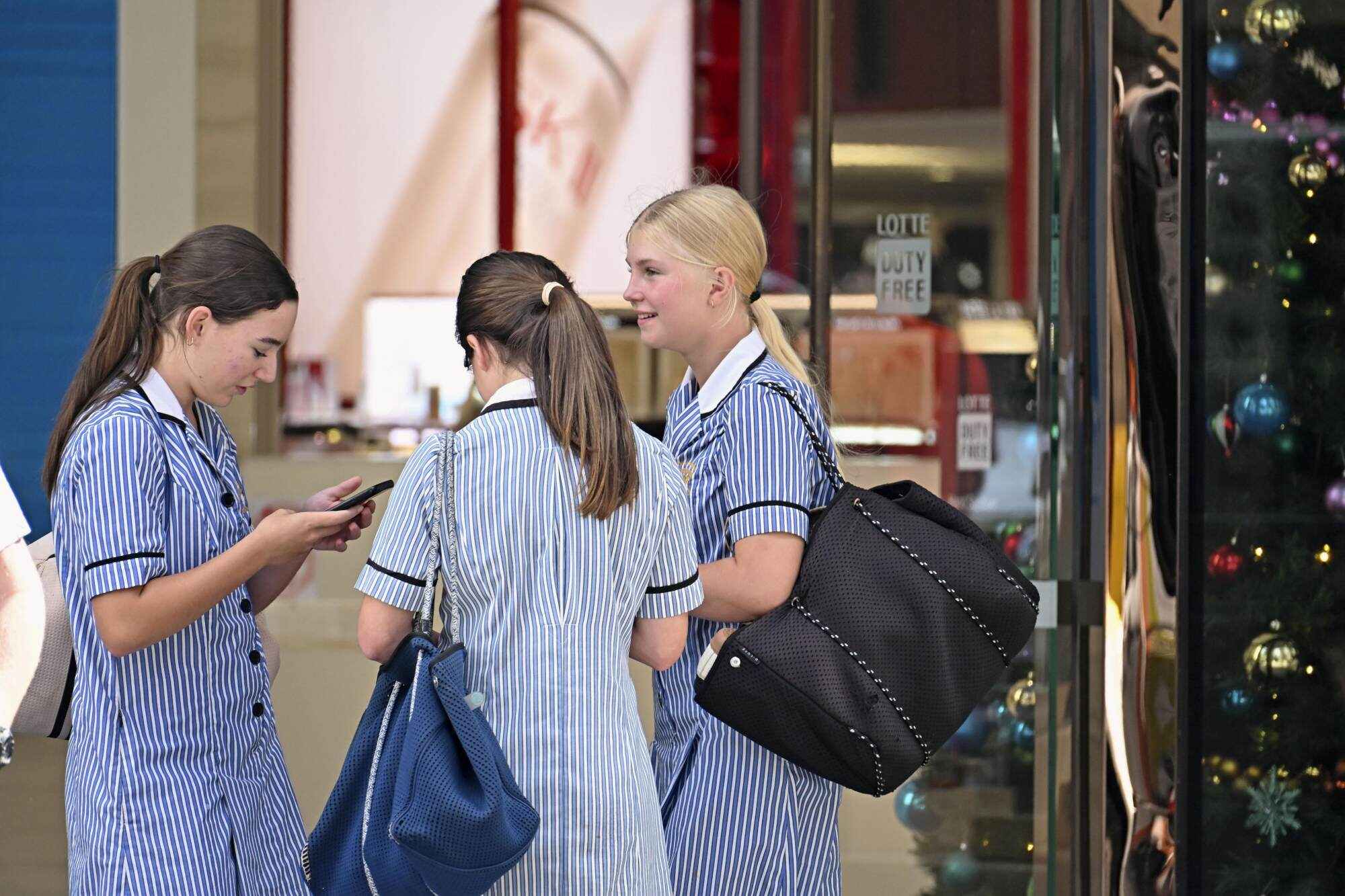 School students chat and look at their smartphones in Sydney, Australia. Photo: Kyodo