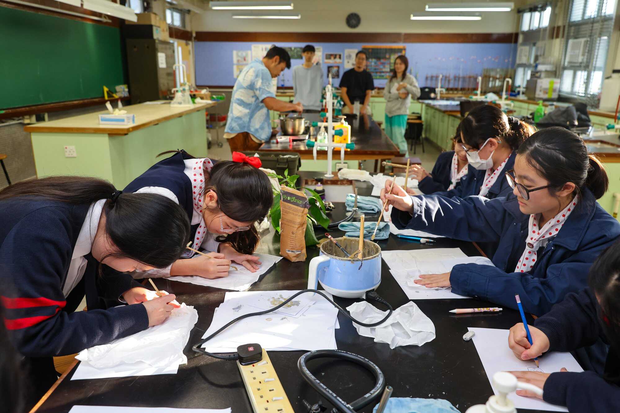 Students use beeswax to create designs on blank fabric. When it is later dunked into the pot of indigo dye, the portions of the cloth with beeswax will not take in the blue colour. Photo: Edmond So
