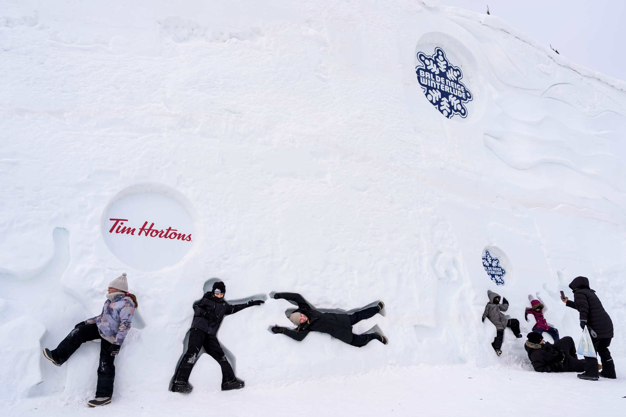 People pose in shapes cut into the snow wall at Snowflake Kingdom at Jacques-Cartier Park in Gatineau, Que., on the first weekend of Winterlude, on Saturday, Jan. 31, 2026. (Justin Tang /The Canadian Press via AP)