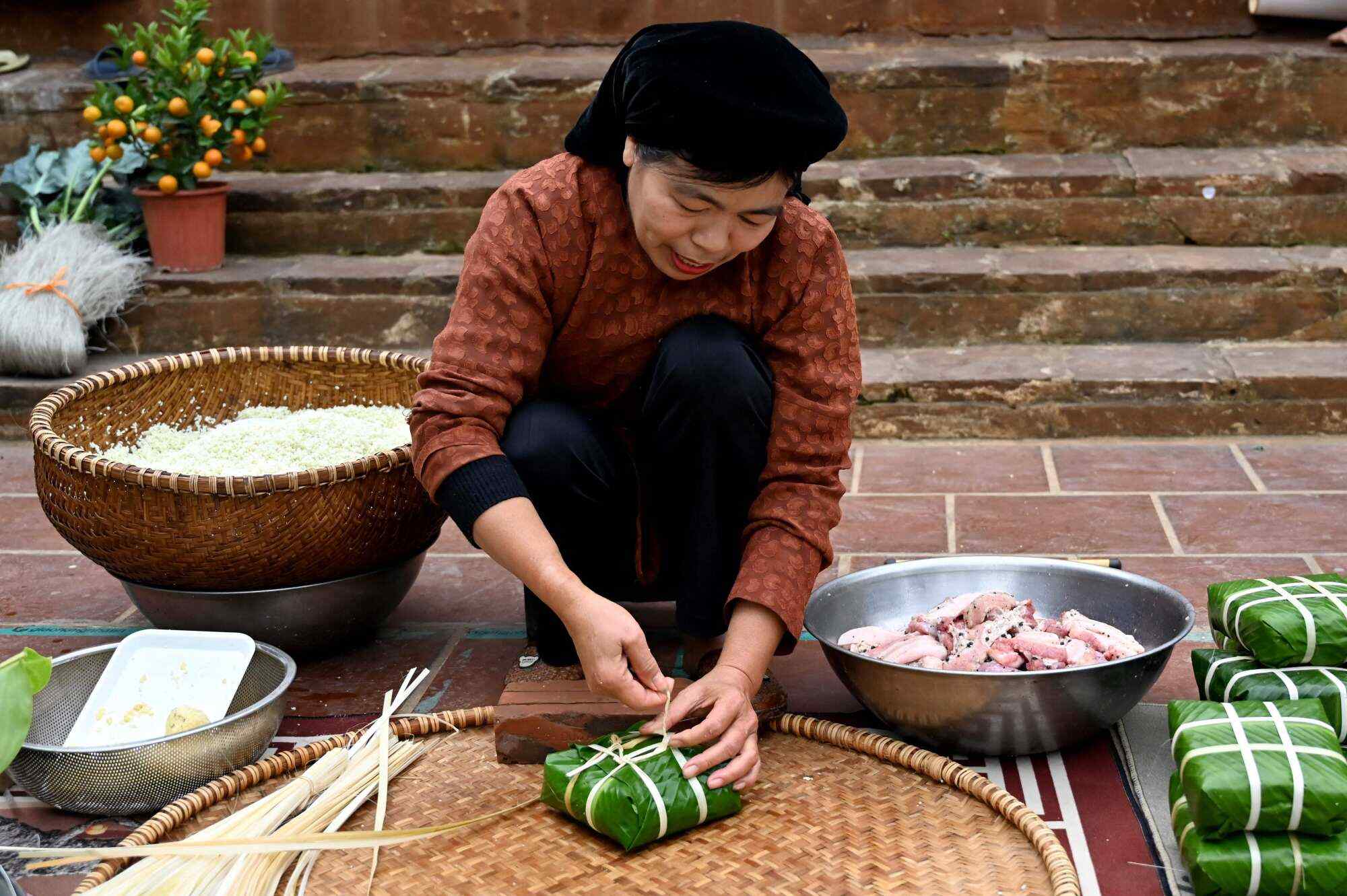 A woman prepares banh chung rice cakes for Tet in Vietnam. Photo: AFP