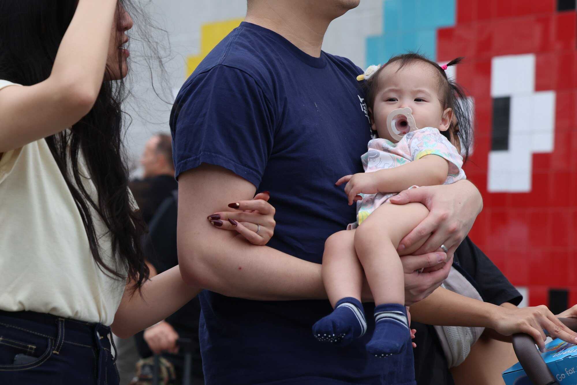 A man with a baby in his hands passes by the Tsim Sha Tsui waterfront. Photo: Jelly Tse