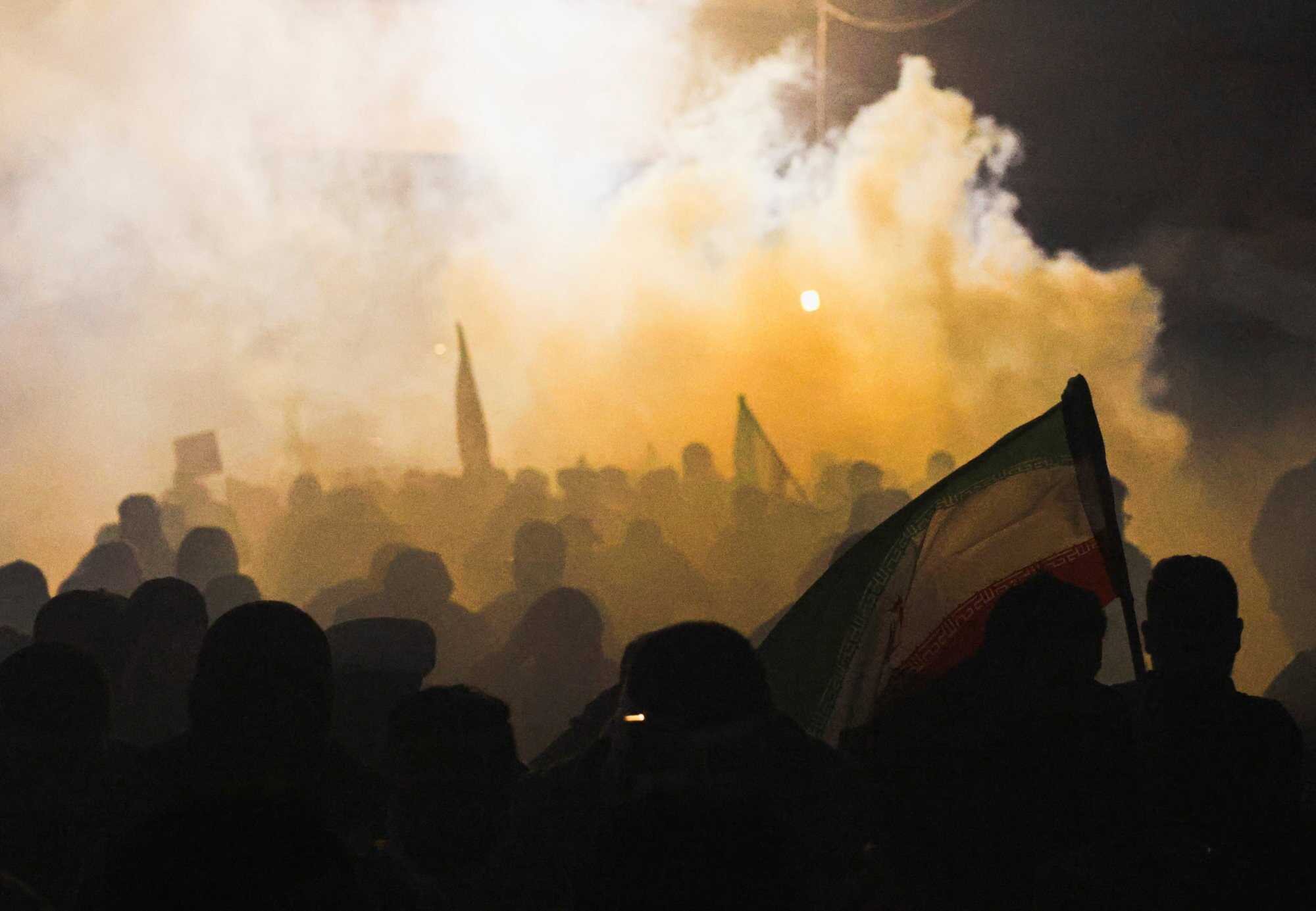 Protesters supporting Iraqi Shia armed groups stand amid tear gas as they attempt to move toward the US embassy located in Baghdad’s Green Zone, as riot police deploy to block their advance in Baghdad, Iraq. Photo: Reuters