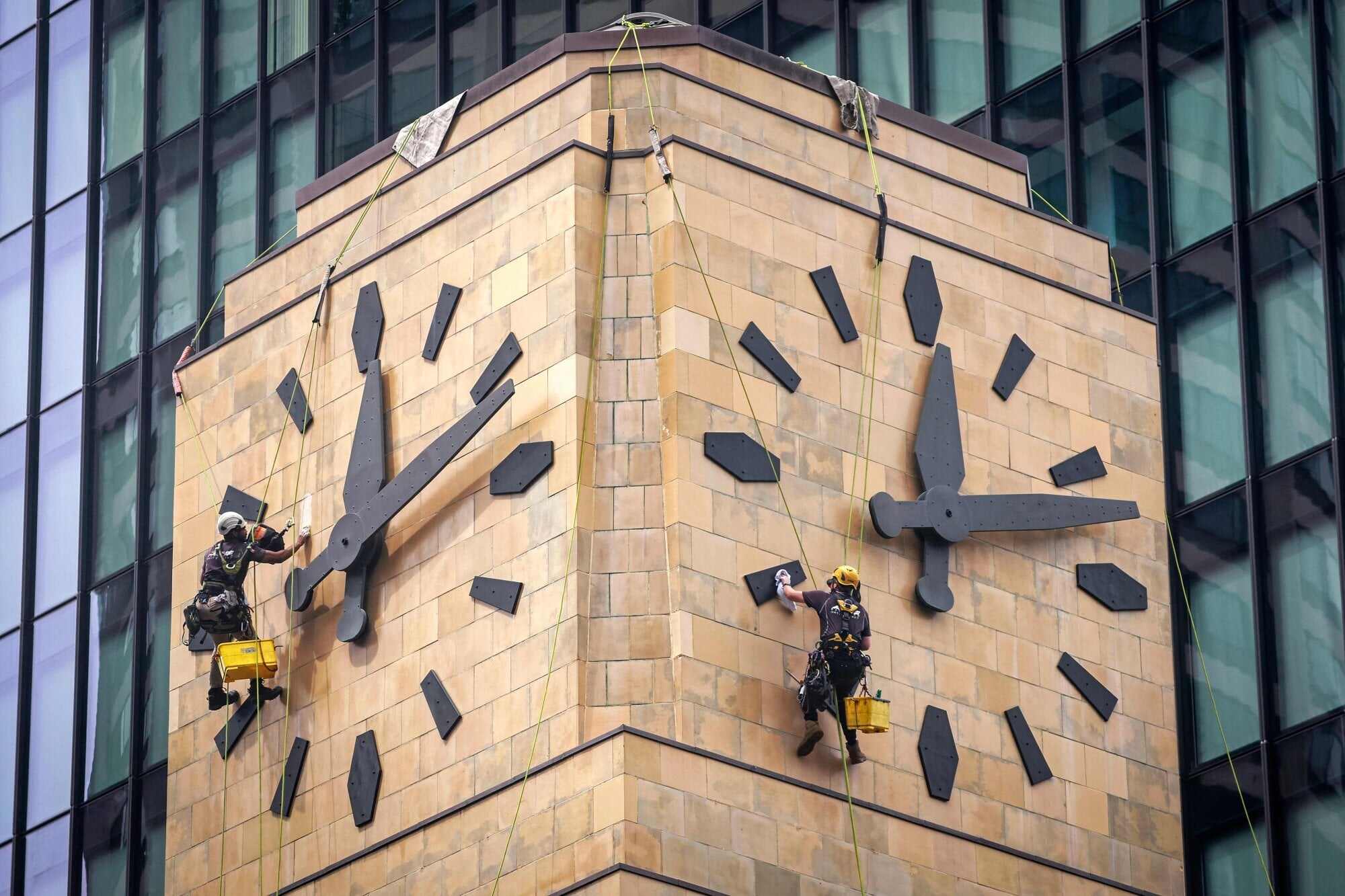 Workers hang from ropes as they clean the historic Shell House clock tower in central Sydney. Photo: AFP