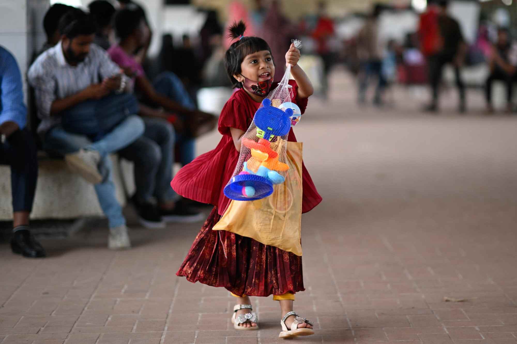 A young girl shows off her toys as she and her family wait to board a train at the Kamalapur Railway Station in Dhaka, Bangladesh. Photo: AP