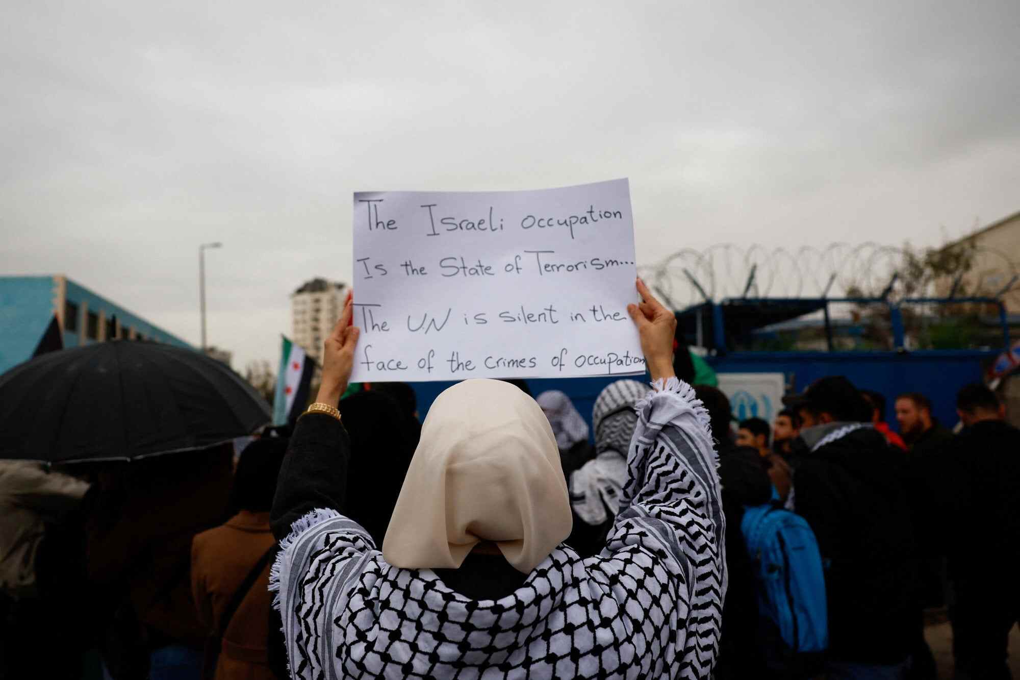 A woman holds a sign as protesters gather outside the office of the United Nations High Commissioner for Refugees to condemn the Israeli death penalty law for Palestinians convicted of lethal attacks, in Damascus, Syria. Photo: Reuters