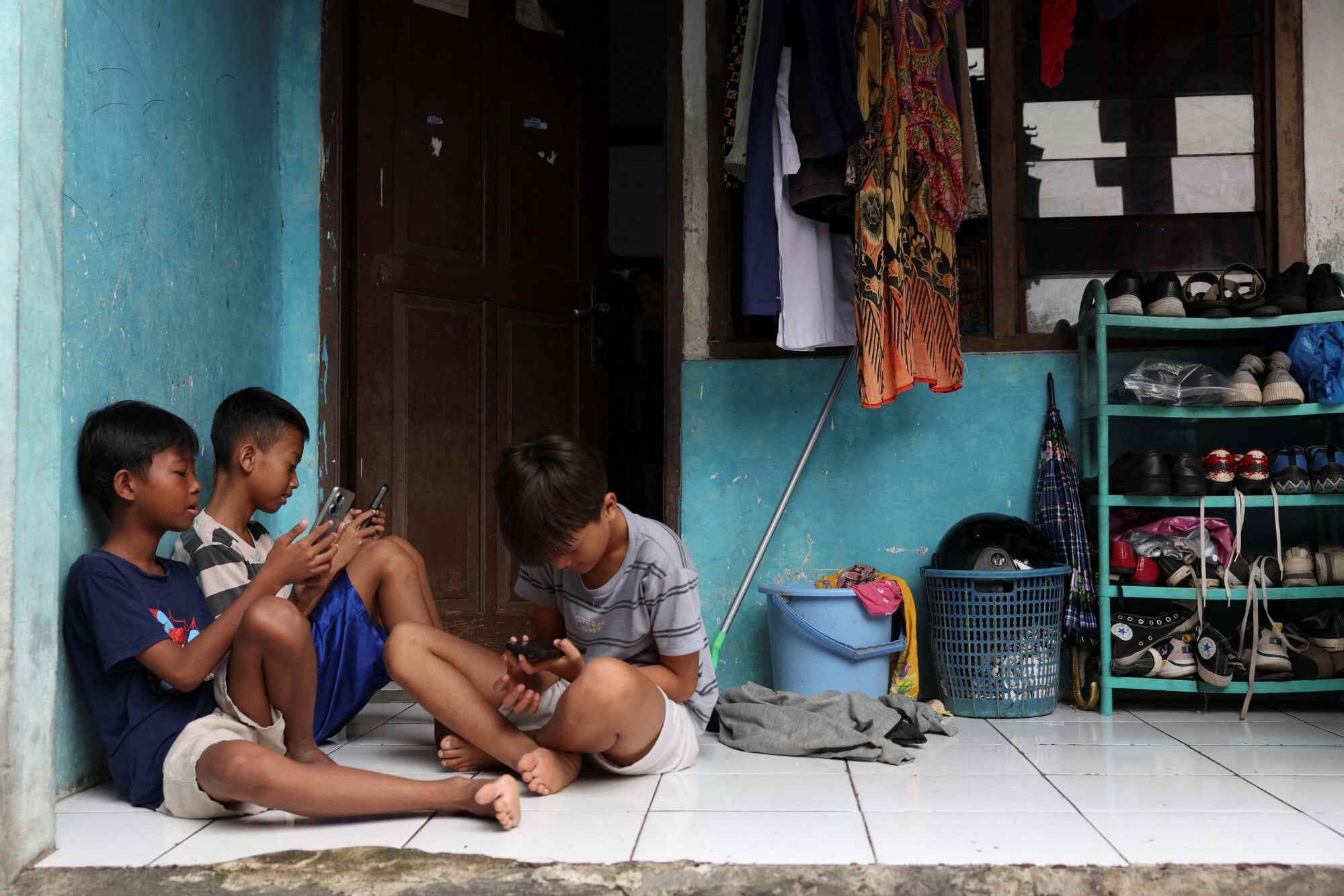 Indonesian children use their phones on the outskirts of Jakarta. The Indonesian government has estimated that one-third of households lack access to adequate shelter. Photo: Reuters