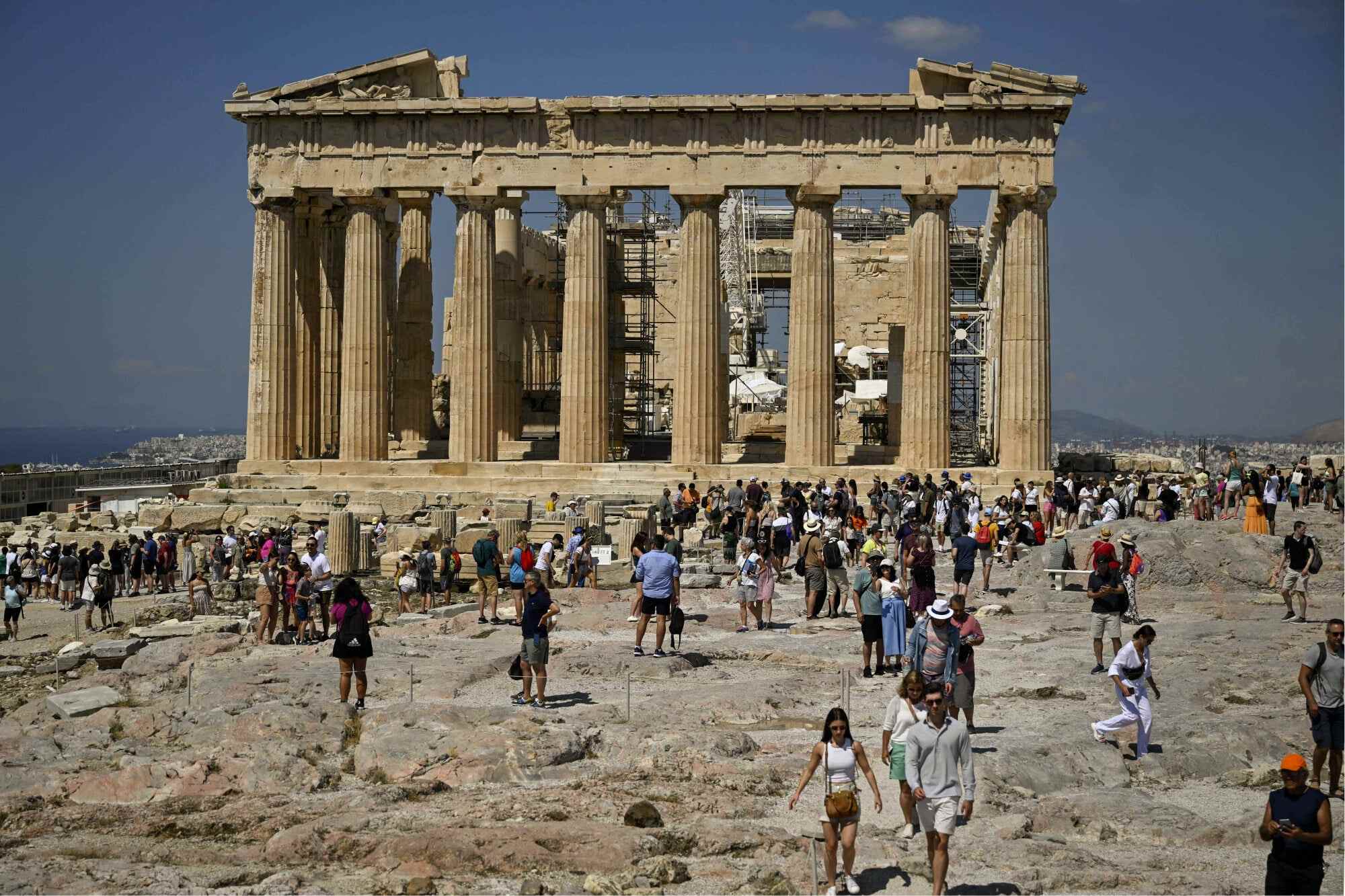 Tourists walk in front of the Parthenon Temple as they visit the Acropolis archaeological site in Athens on June 14, 2023. Greece has already reduced visiting hours at its most popular archaeological site, the Acropolis in Athens, to shield visitors from heatwaves during the warmest hours of the day. Photo: AFP