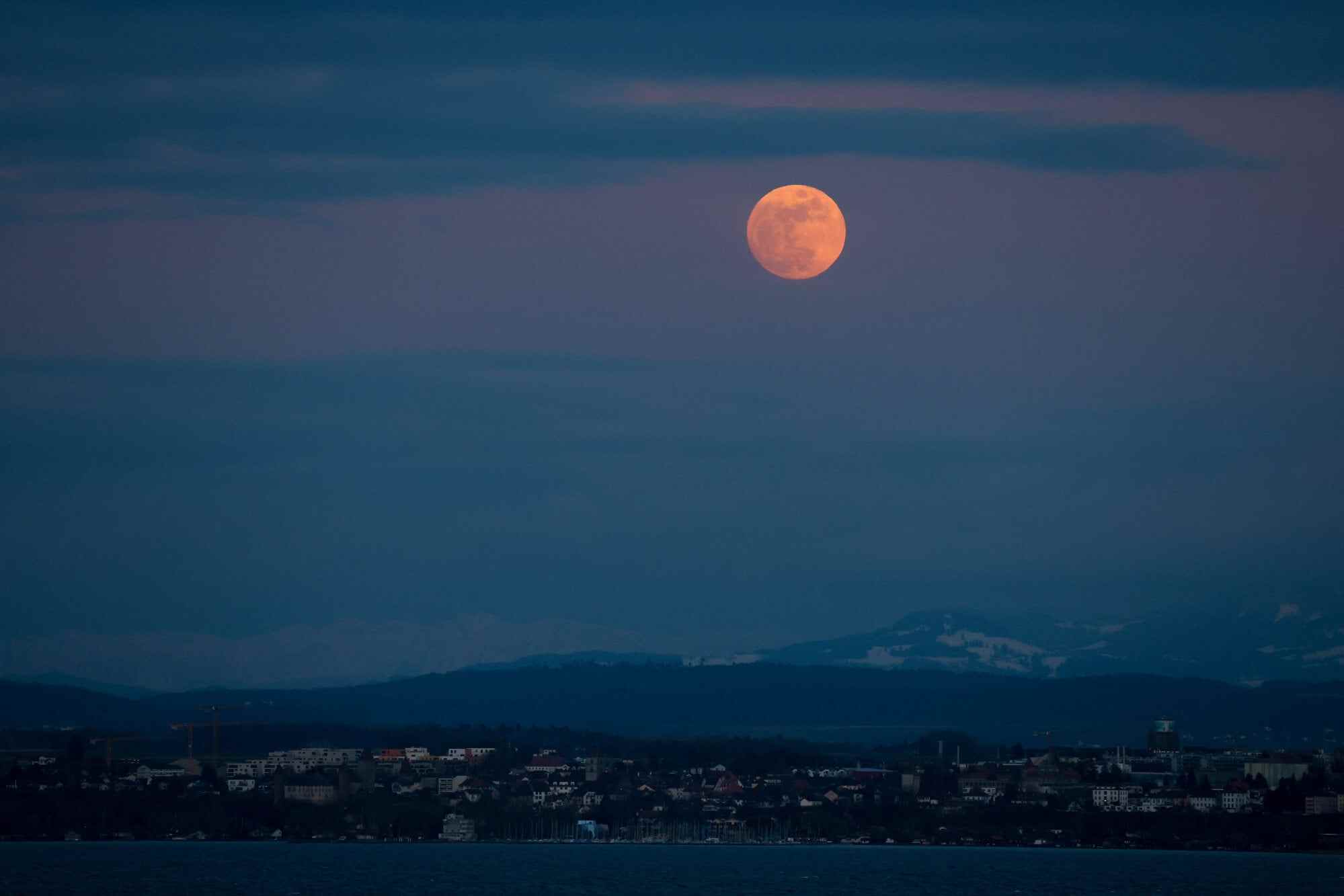 The pink full moon rises above the village of Estavayer and Lake Neuchâtel as seen from Concise, Switzerland on April 1, 2026. Photo: Reuters