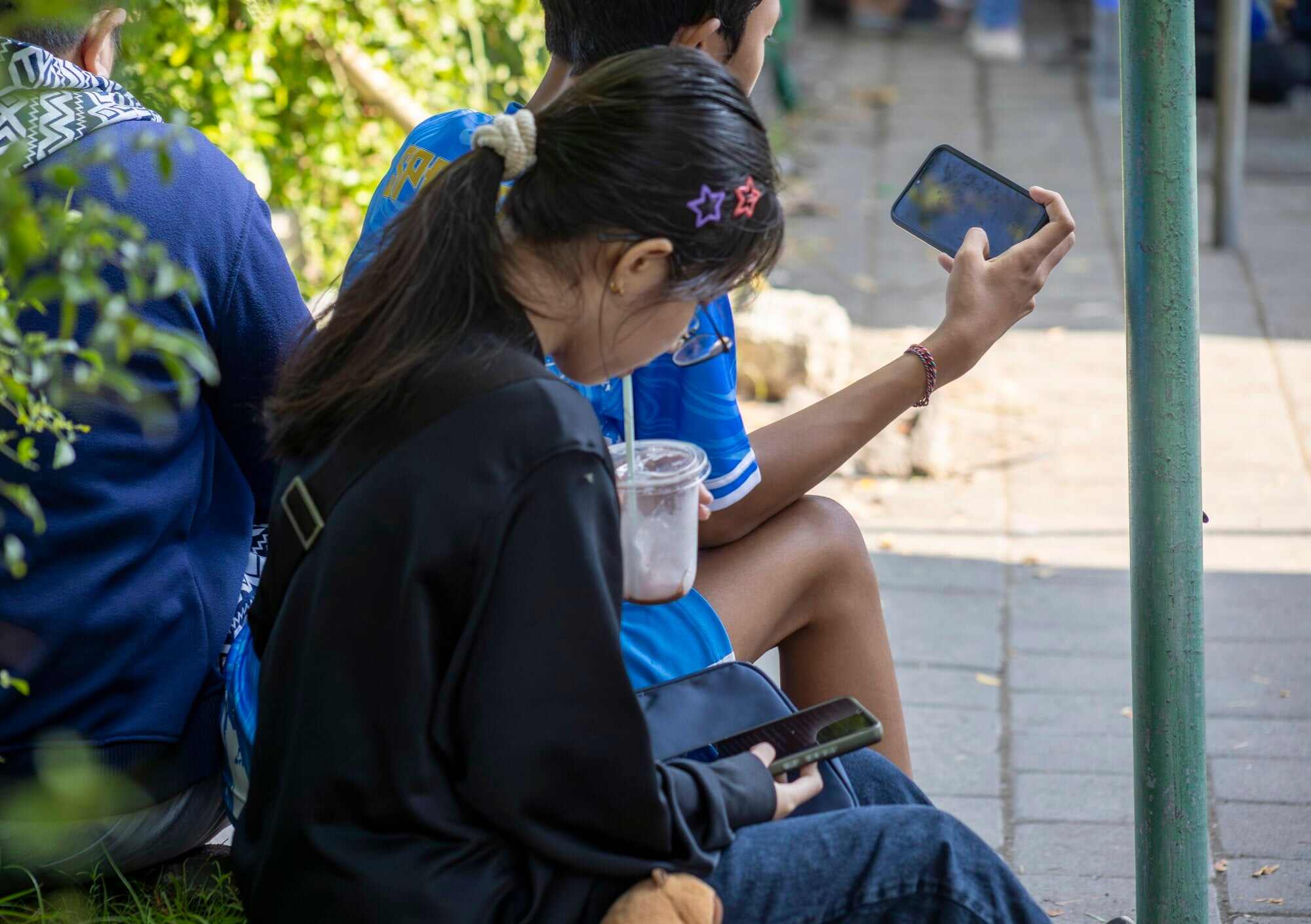 Young people use mobile phones at a park in Denpasar, Bali, Indonesia. The Indonesian government has said its new restriction on social media use for children under 16 is to strengthen online child protection. Photo: EPA