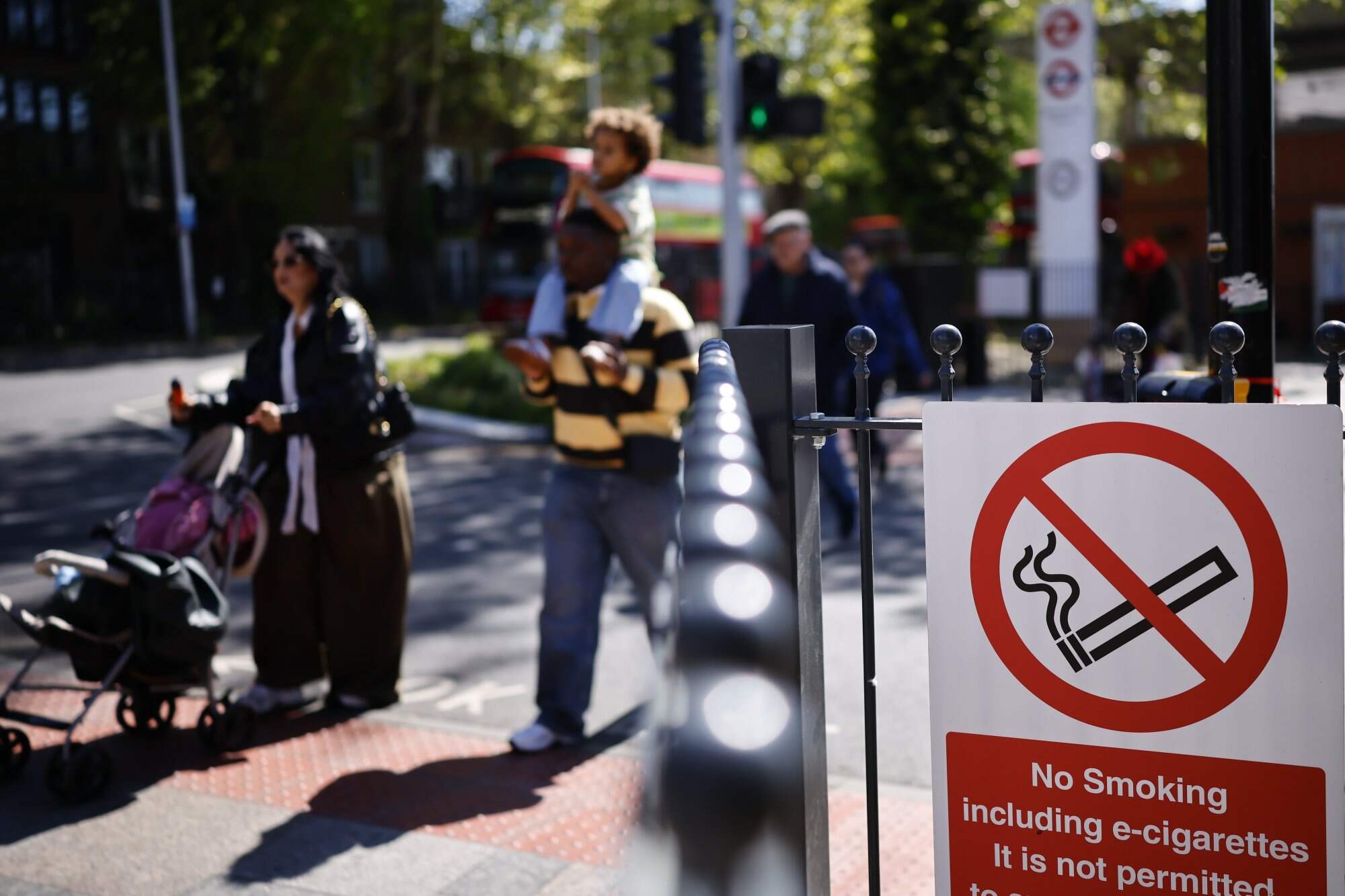 A family walk past a no-smoking sign outside a bus station in East London. The new measures, among the strictest in Europe, aim to create a “smoke-free generation” to save lives and alleviate pressure on the NHS. Photo: EPA