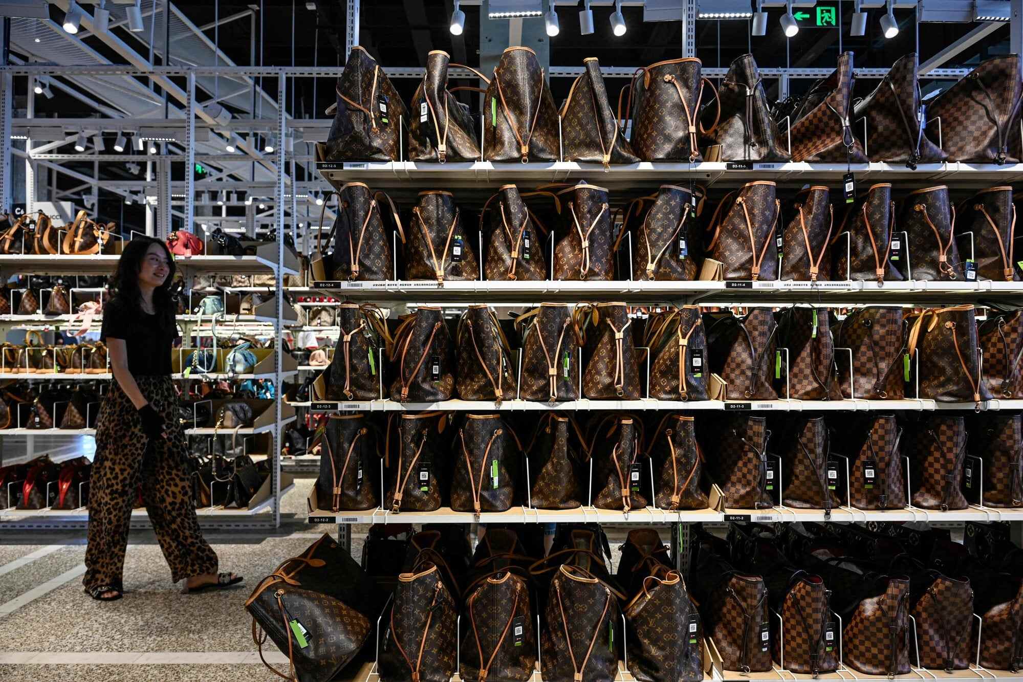 A customer browses through luxury bags in a second-hand shop at a commercial district in Beijing on July 30, 2025. Photo: AFP