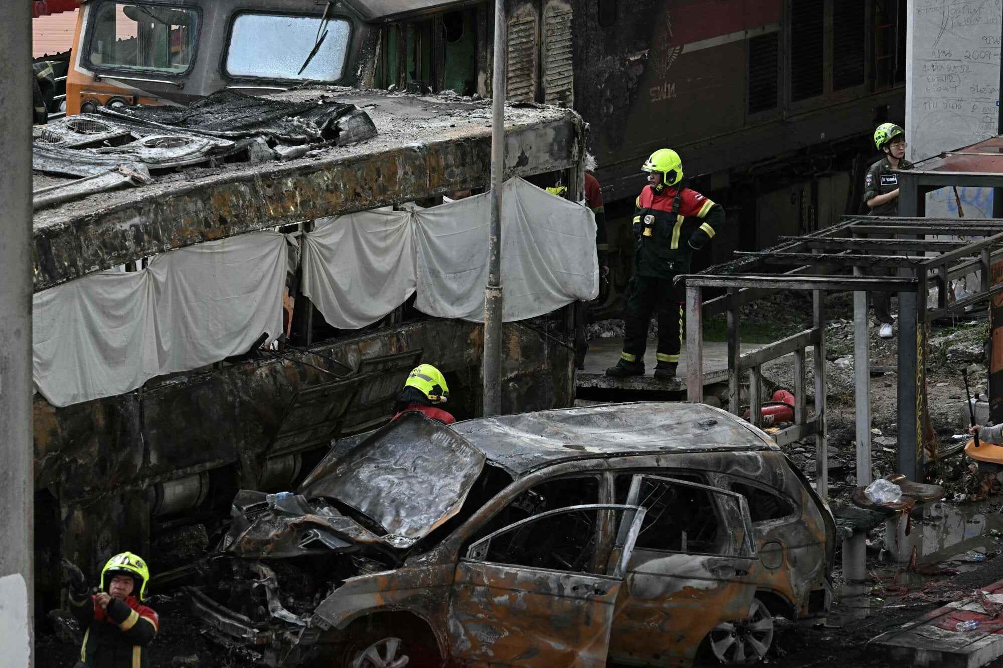 Firefighters and rescue workers surround the aftermath of a train collision with a bus underneath Makkasan Airport Rail Station in Bangkok on May 16. Photo: AFP