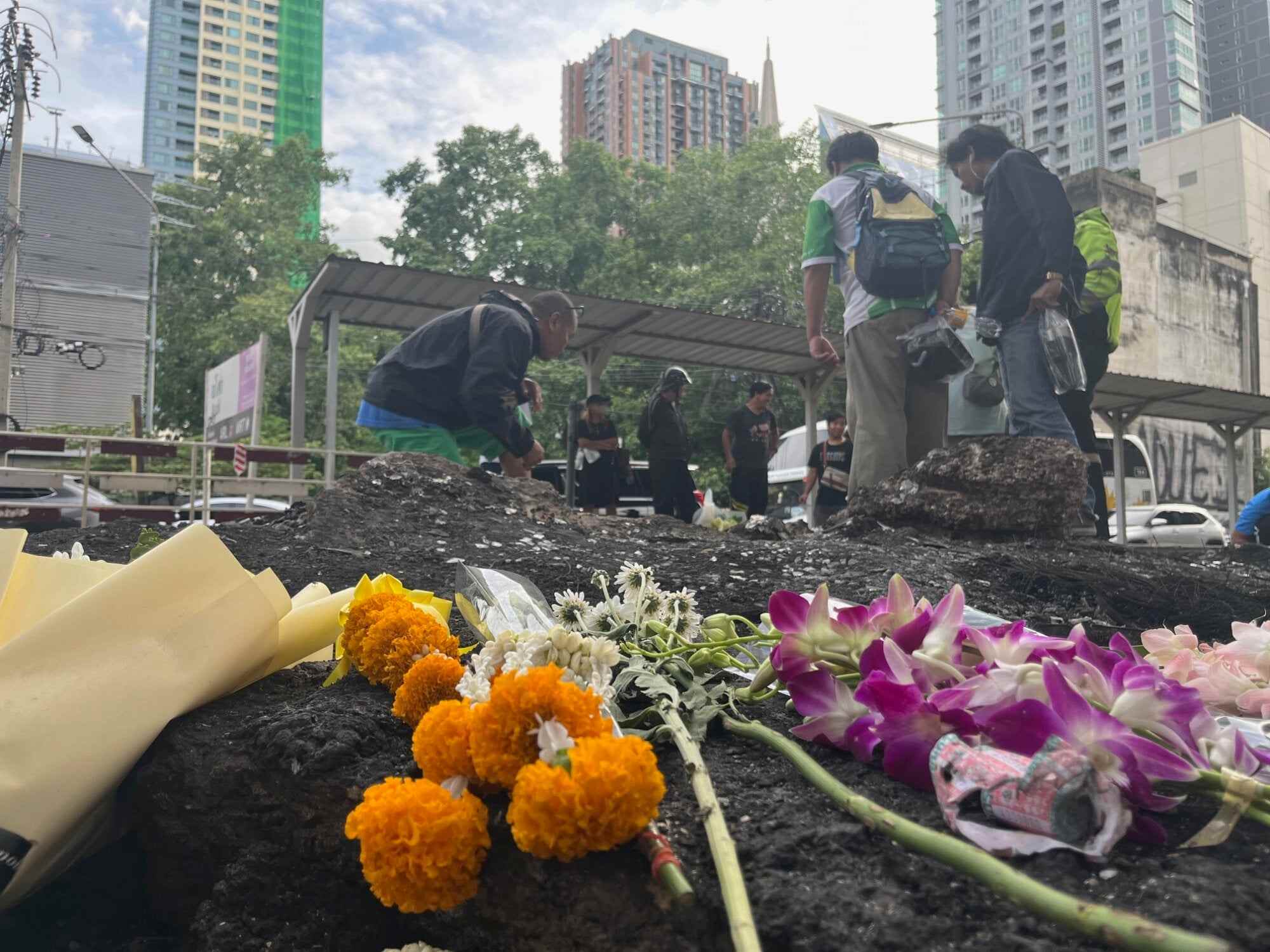 Residents inspect the site of Saturday’s deadly crash, where flowers have been laid in memory of the eight people who died. Photo: Aidan Jones