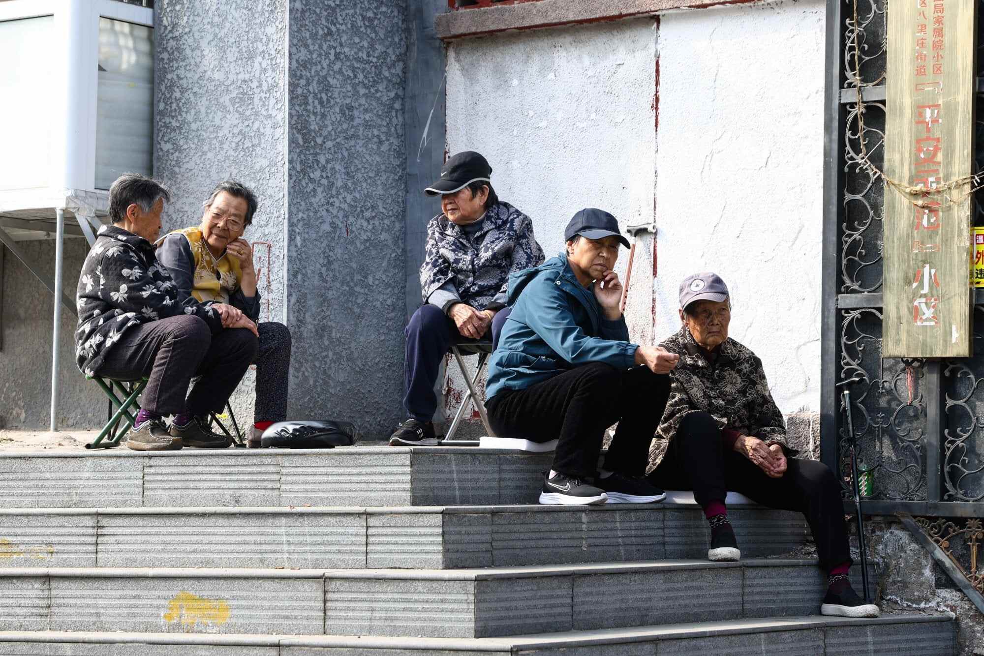 Elderly residents sit and gather on stairs along a street in Beijing, China. Photo: EPA