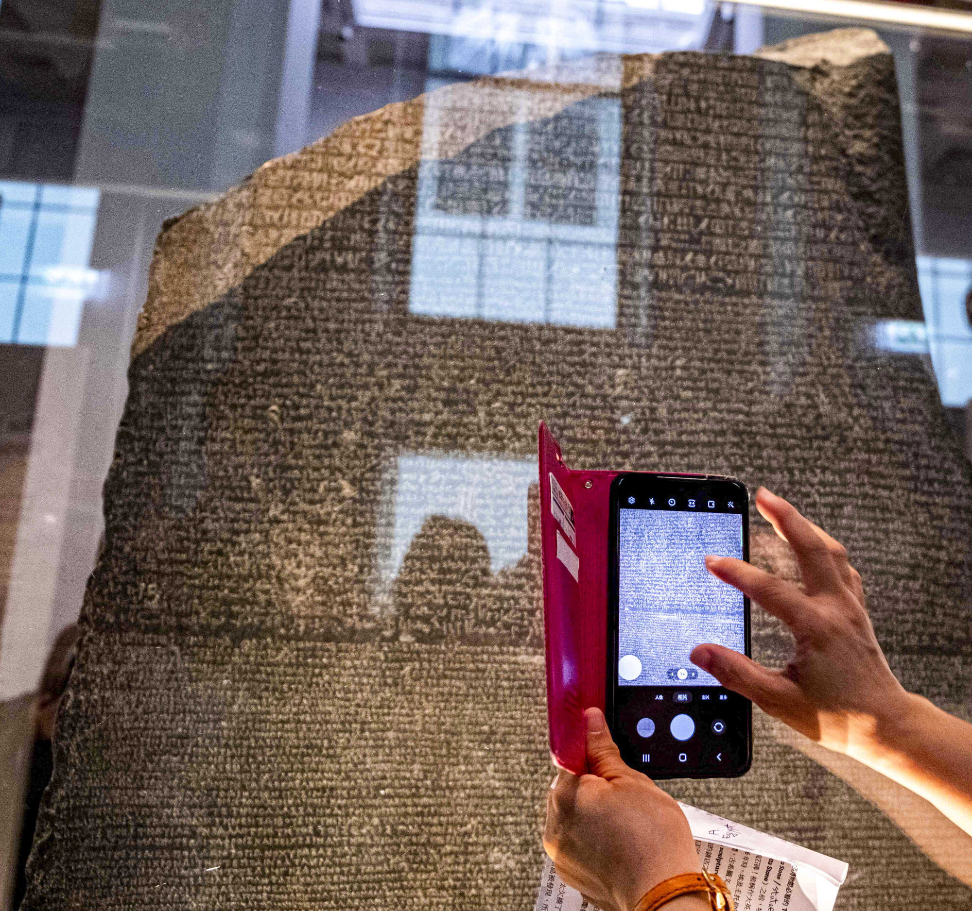 A visitor uses a phone to take pictures of the Rosetta Stone at the British Museum in London on July 26, 2022. Photo: AFP