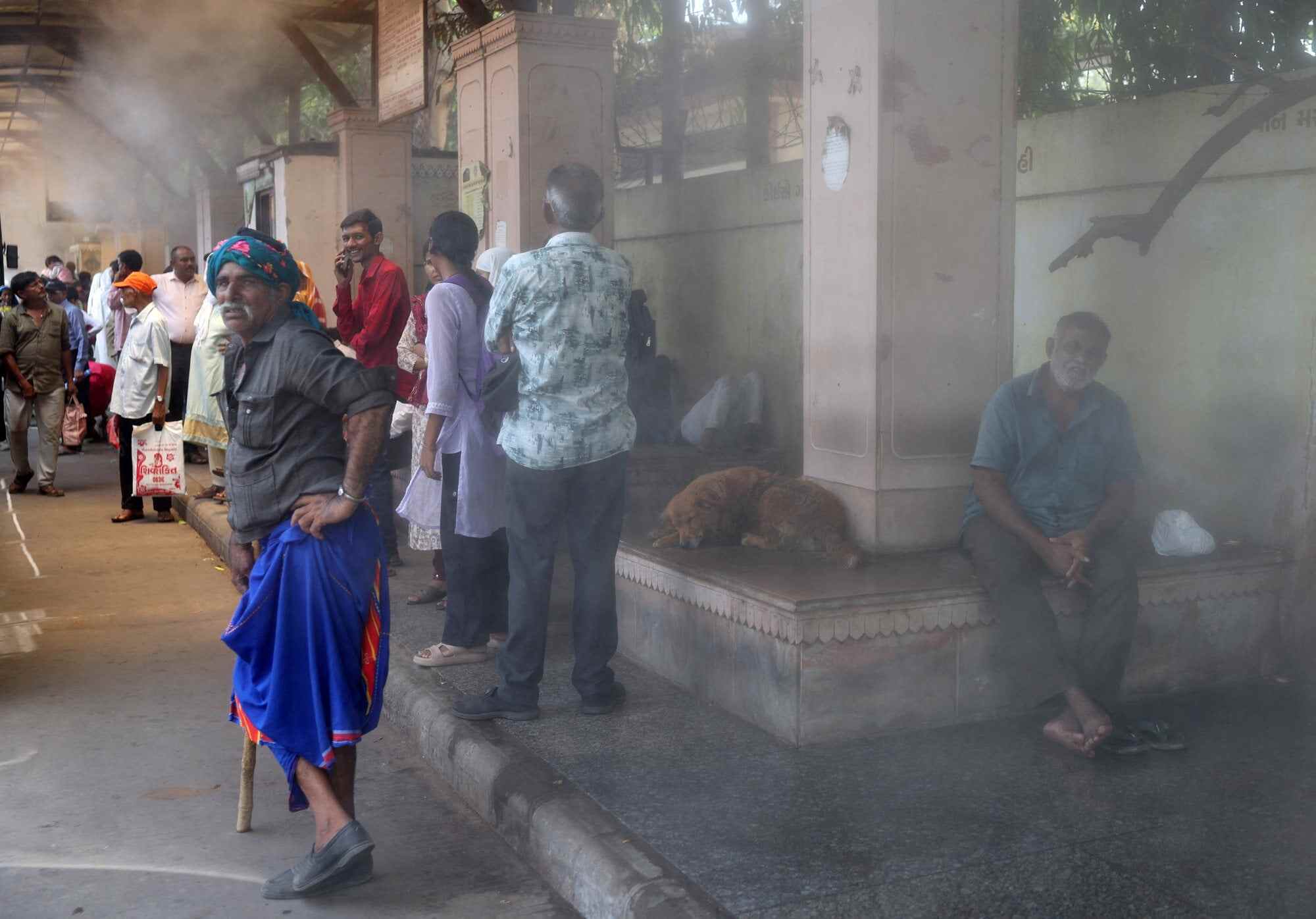 Passengers wait at a bus stop equipped with water mist to provide relief from heat in Ahmedabad, India, on June 5. Photo: Reuters