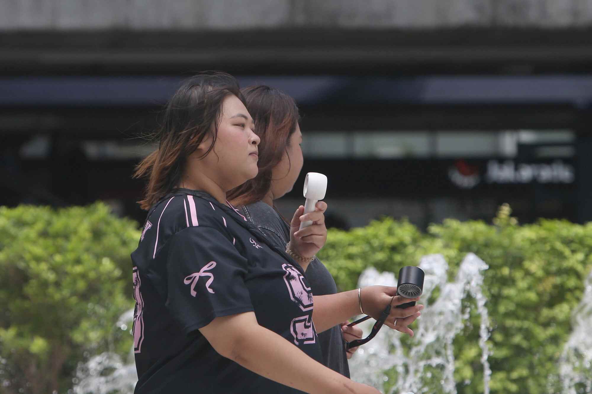 Pedestrians use portable fans while walking on a street in Bangkok, Thailand, last Tuesday. Photo: Xinhua