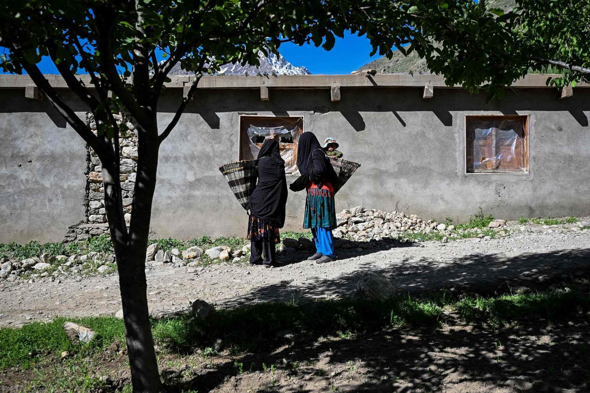 Habiba speaks to a resident while carrying her granddaughter, Saeeda, on her way to work in a field in Eshtiwi. Photo: AFP