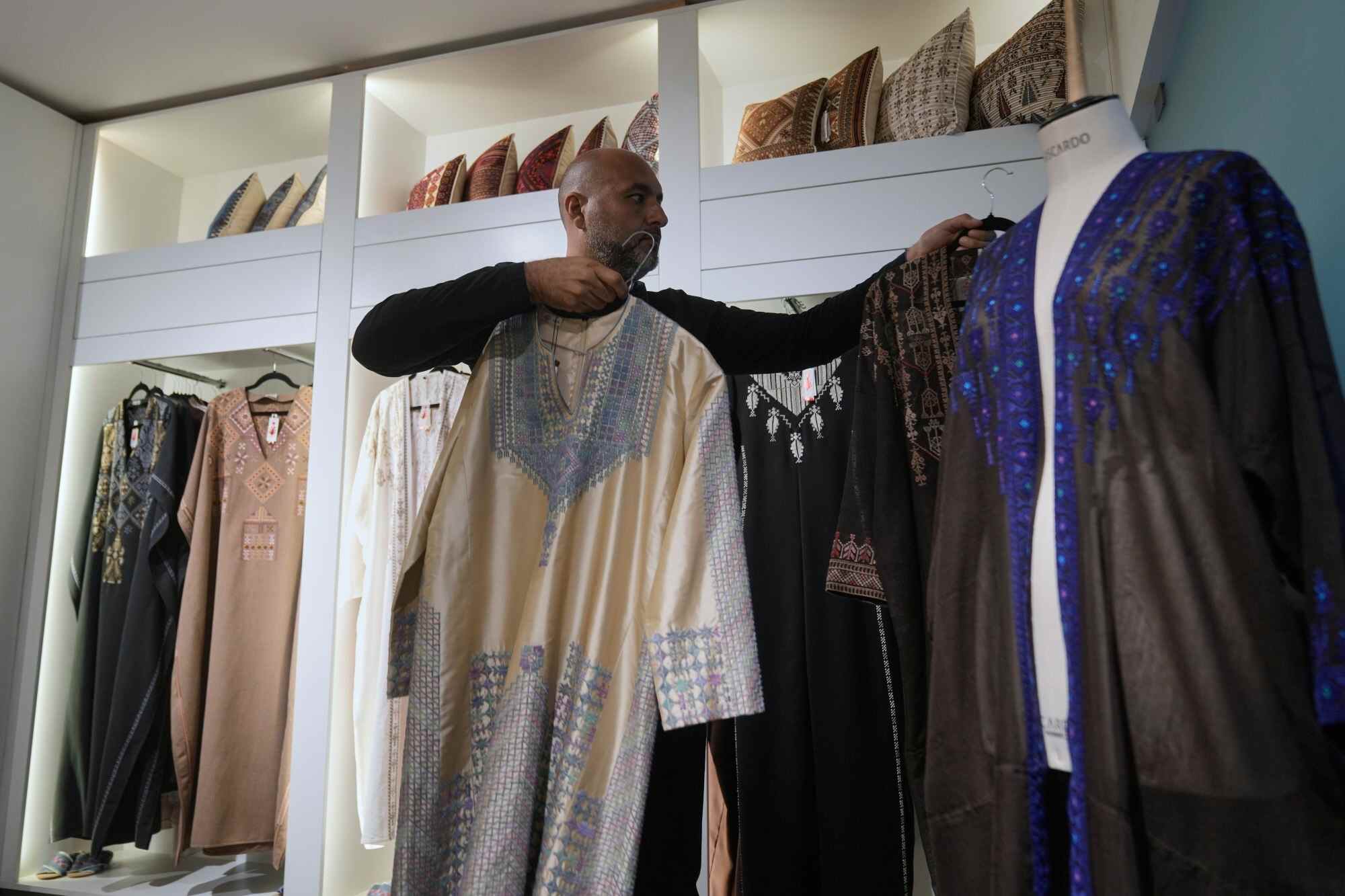 Ali Jaafar, the general manager of Inaash Association, arranges clothes at the embroidery workshop. Photo: AP