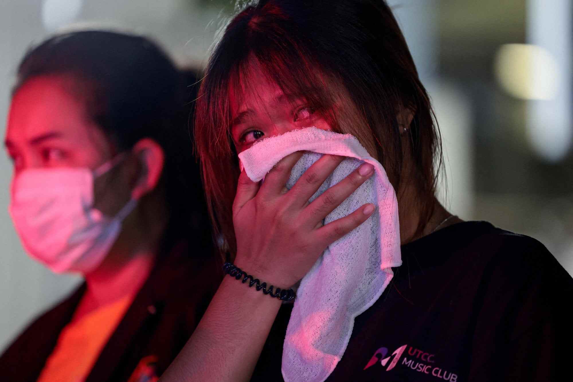 A woman, whose older sister died in the fire, holds a cloth to her face near the scene in Bangkok, Thailand, on Monday. Photo: Reuters