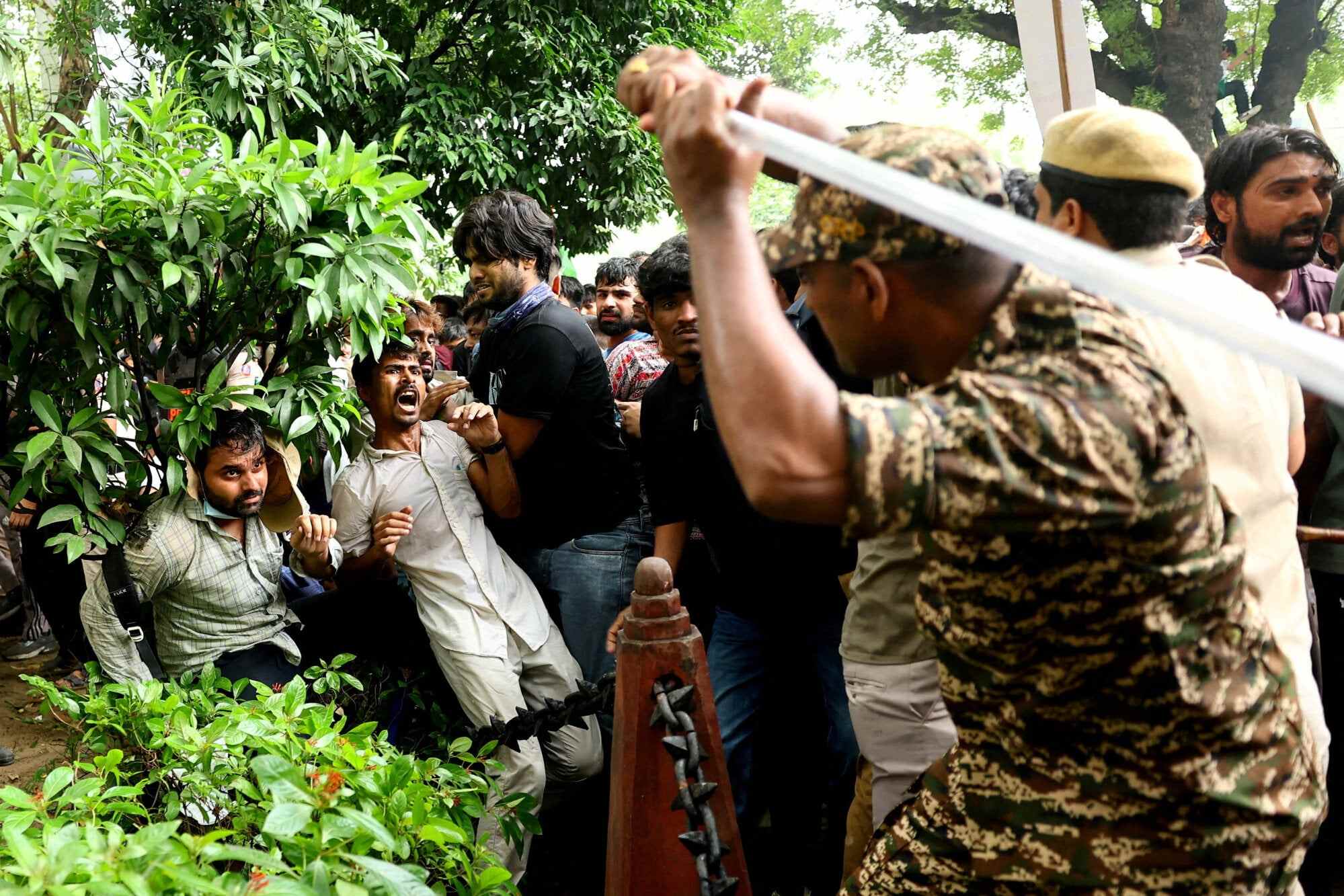 A security force personnel wields his baton against demonstrators at a protest site near Jantar Mantar, New Delhi. Photo: Reuters