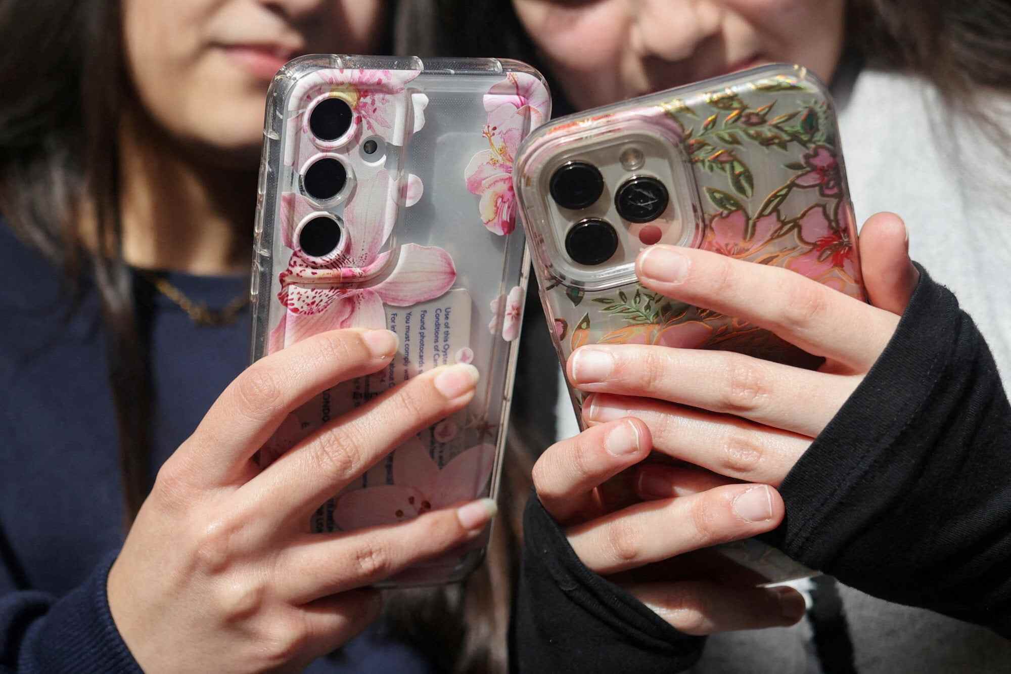 Students Dua, 16 and Awand, 17, from Ricards Lodge High School in Wimbledon pose with their mobile phones in London. In June, the United Kingdom announced that under-16s would be banned from a range of social media platforms. Photo: Reuters