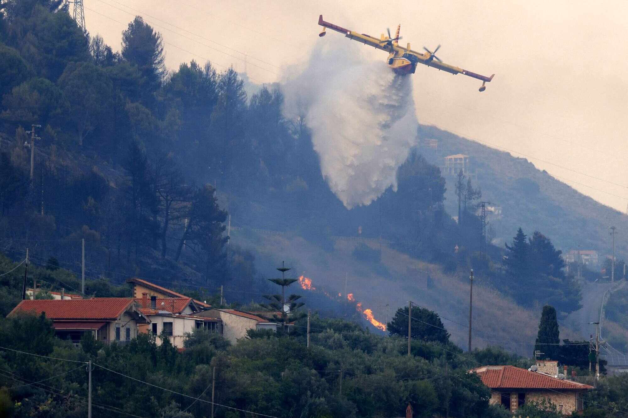 A Canadair drops water over a burning area as a wildfire flares in Sagana in the territory of Monreale, Sicily on July 22, 2026. Photo: AFP