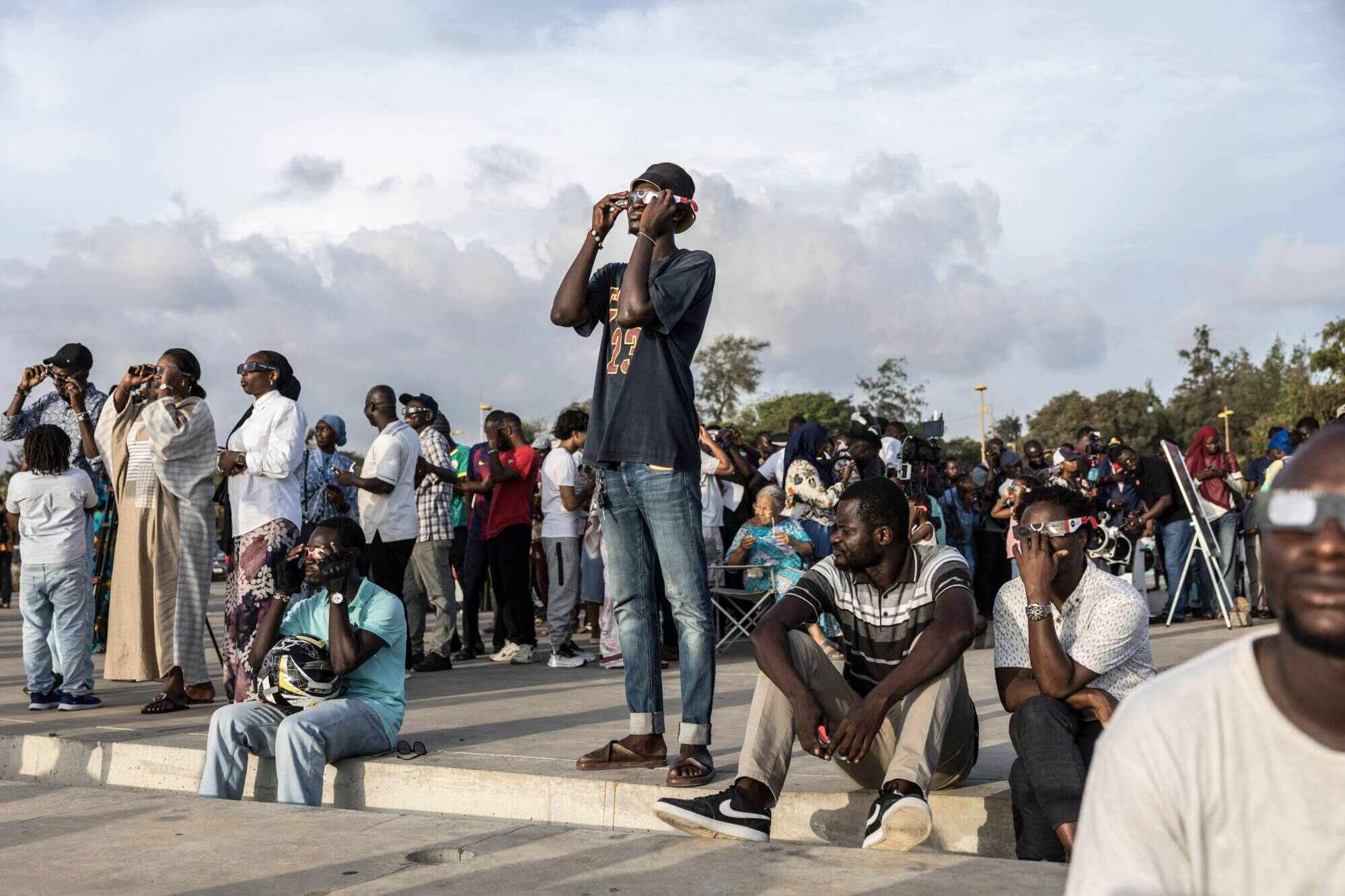 People watch through solar eclipse viewing glasses as the moon passes over the sun’s horizon during a partial solar eclipse in Dakar, Senegal on August 12, 2026. Photo: AFP