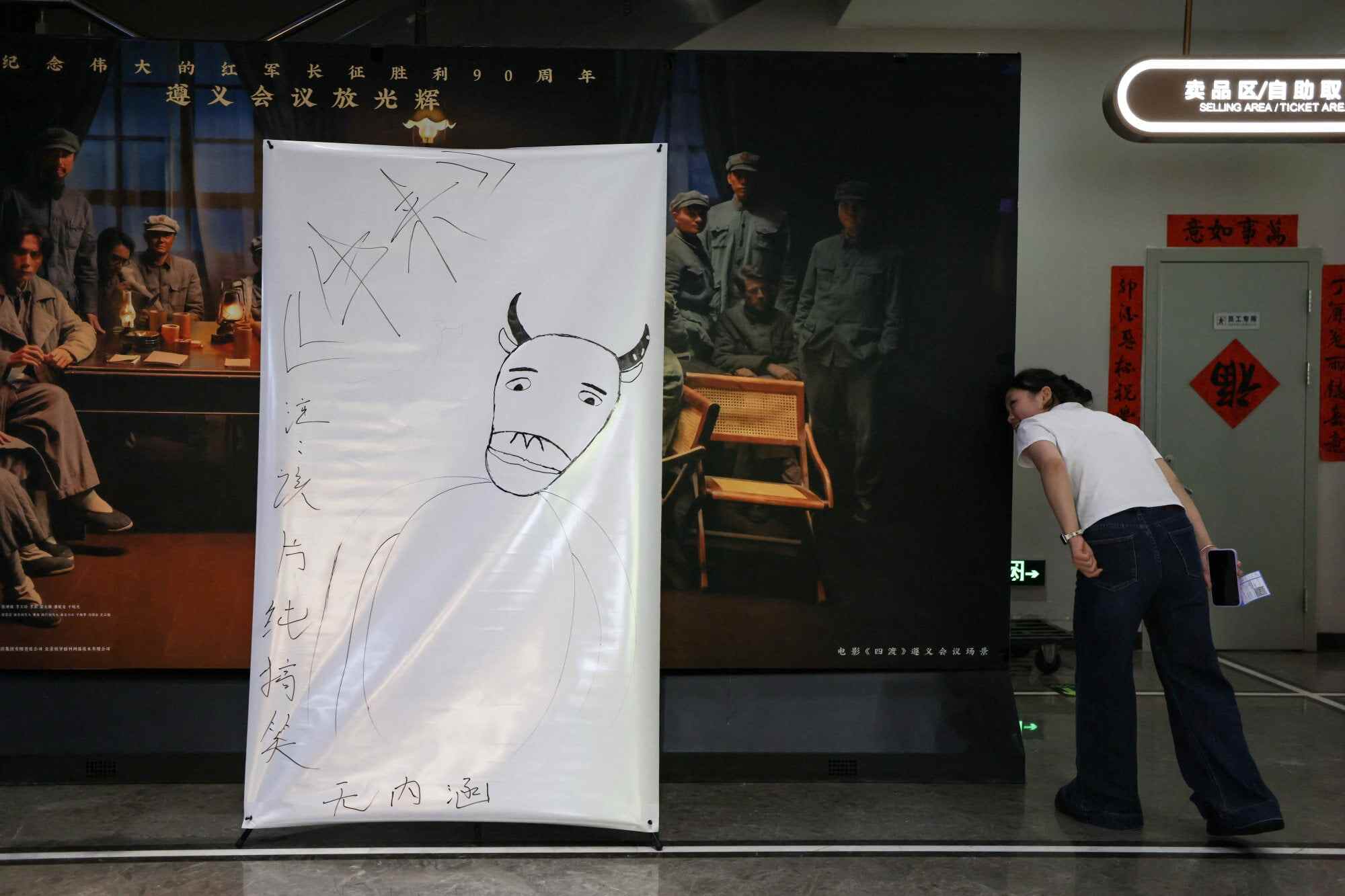 A person checks the back of a hand-drawn poster for the Chinese animated film Niu Lai. Its unpolished style quickly went viral on social media, with fans embracing its imperfections as part of its charm. Photo: Reuters